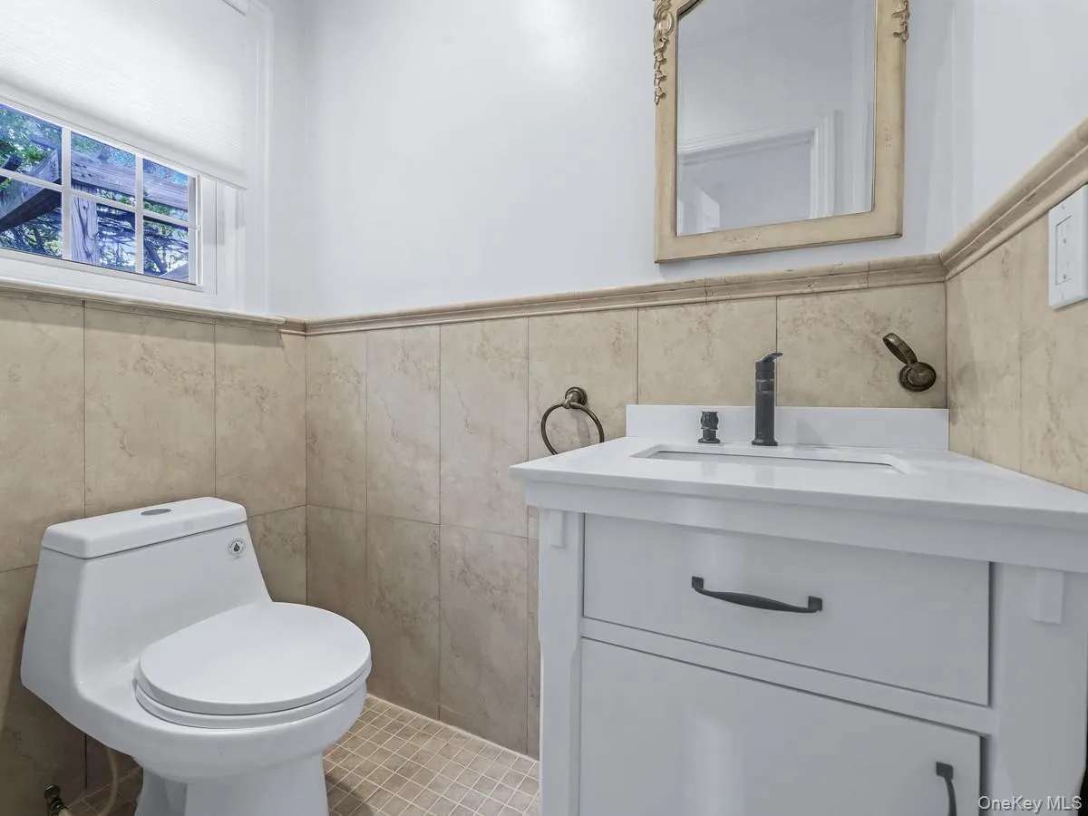 Bathroom featuring a wainscoted wall, vanity, and tile walls Bathroom featuring a wainscoted wall, vanity, and tile walls