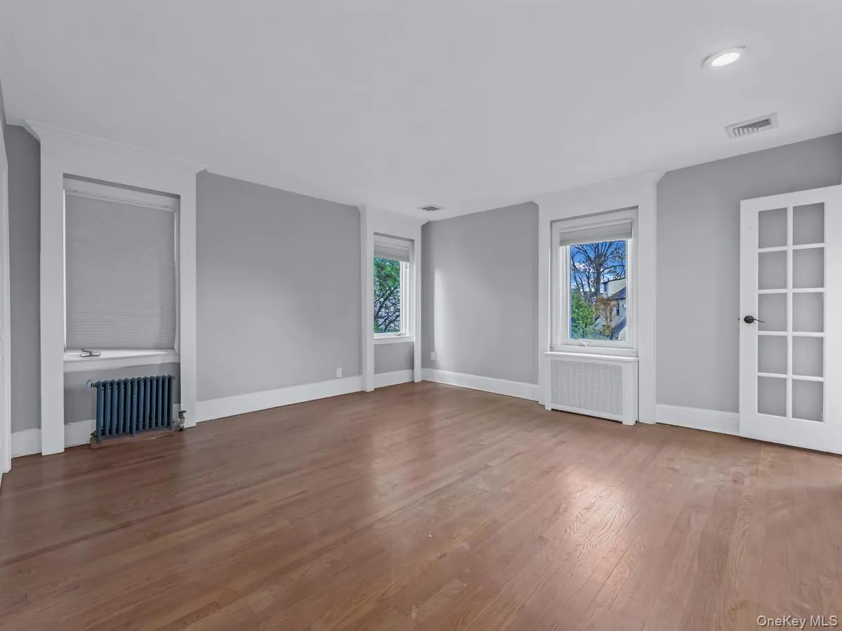 Spare room featuring radiator heating unit and light wood finished floors Spare room featuring radiator heating unit and light wood finished floors