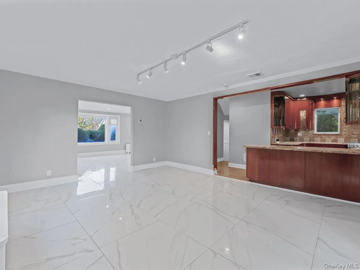 Unfurnished living room featuring light marble finish floors and rail lighting Unfurnished living room featuring light marble finish floors and rail lighting