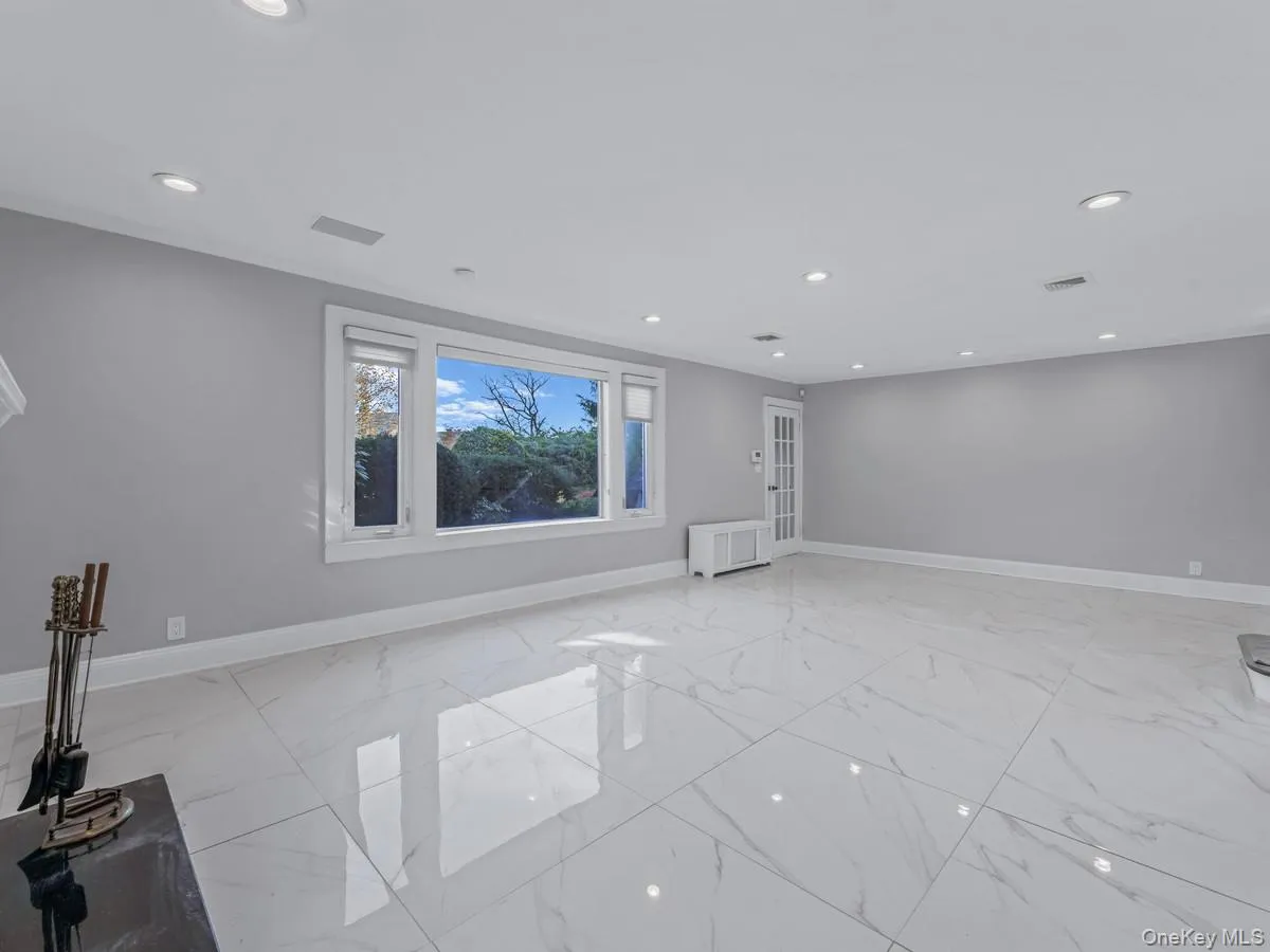 Empty room featuring light marble finish floors, recessed lighting, and radiator Empty room featuring light marble finish floors, recessed lighting, and radiator