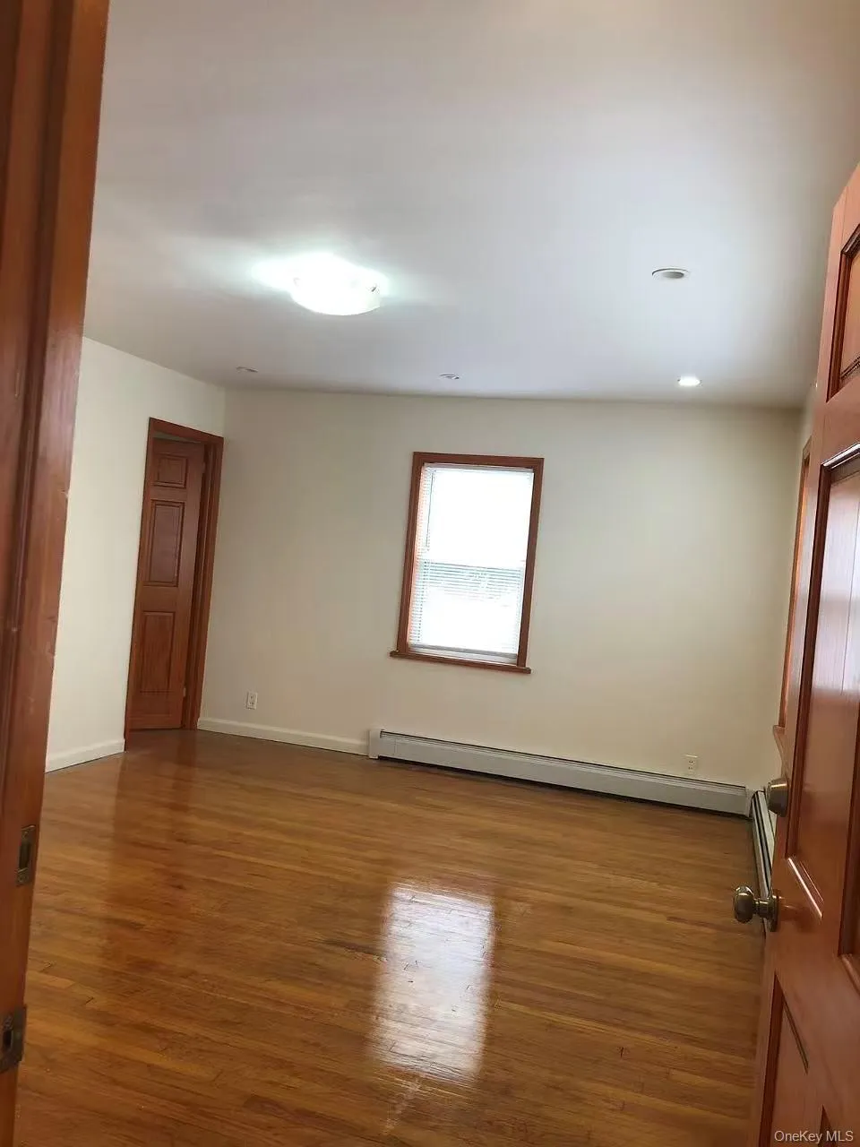 Empty room featuring dark wood finished floors and a baseboard heating unit Empty room featuring dark wood finished floors and a baseboard heating unit
