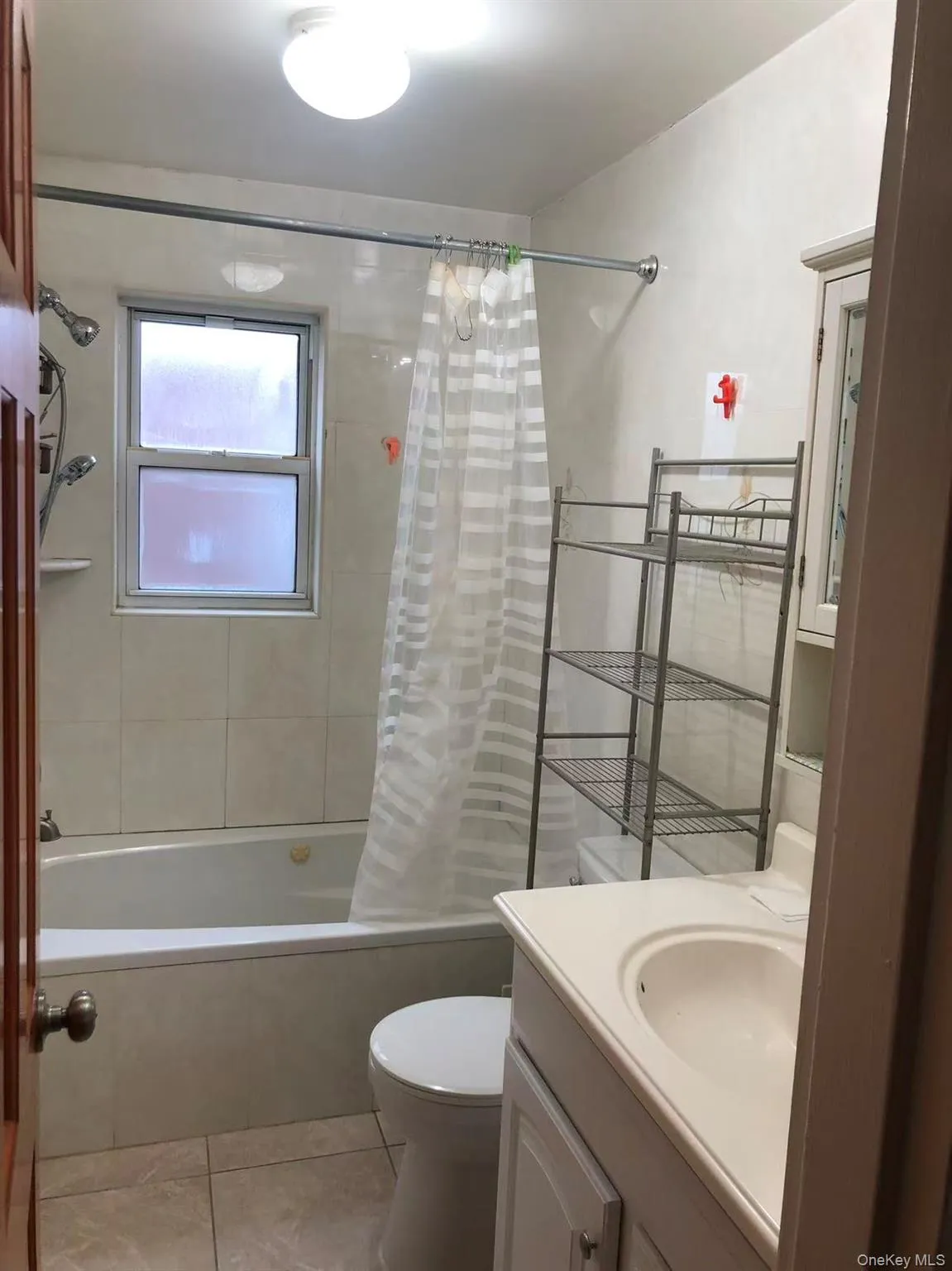 Bathroom featuring shower / bath combination with curtain, vanity, and light tile patterned floors Bathroom featuring shower / bath combination with curtain, vanity, and light tile patterned floors