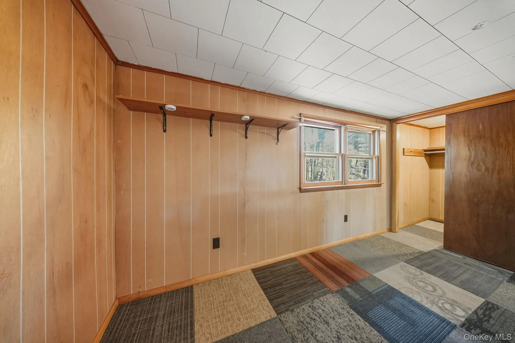 Unfurnished bedroom featuring wood walls and a walk in closet Unfurnished bedroom featuring wood walls and a walk in closet