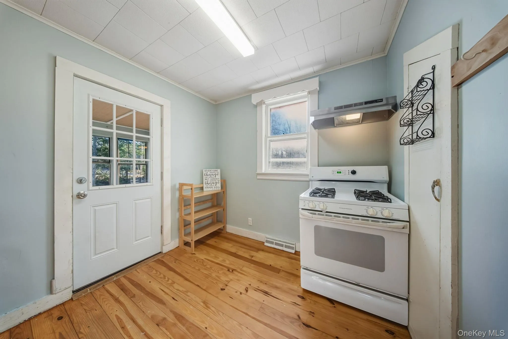 Kitchen featuring white range with gas stovetop, under cabinet range hood, plenty of natural light, and light wood-style flooring Kitchen featuring white range with gas stovetop, under cabinet range hood, plenty of natural light, and light wood-style flooring
