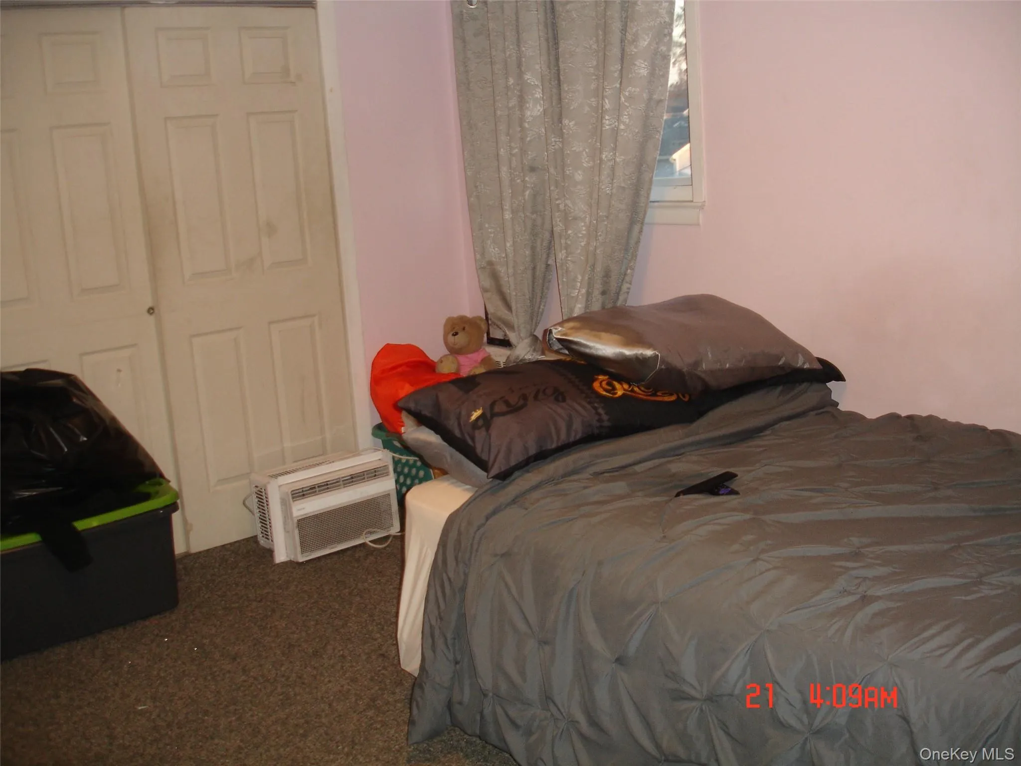 Bedroom with an AC wall unit and dark carpet Bedroom with an AC wall unit and dark carpet