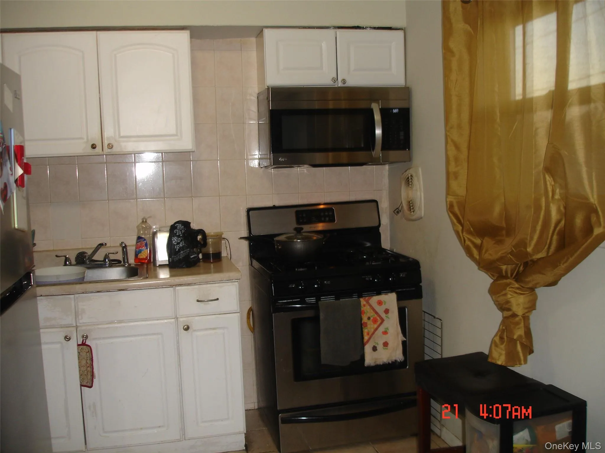 Kitchen featuring white cabinets, appliances with stainless steel finishes, decorative backsplash, and light countertops Kitchen featuring white cabinets, appliances with stainless steel finishes, decorative backsplash, and light countertops