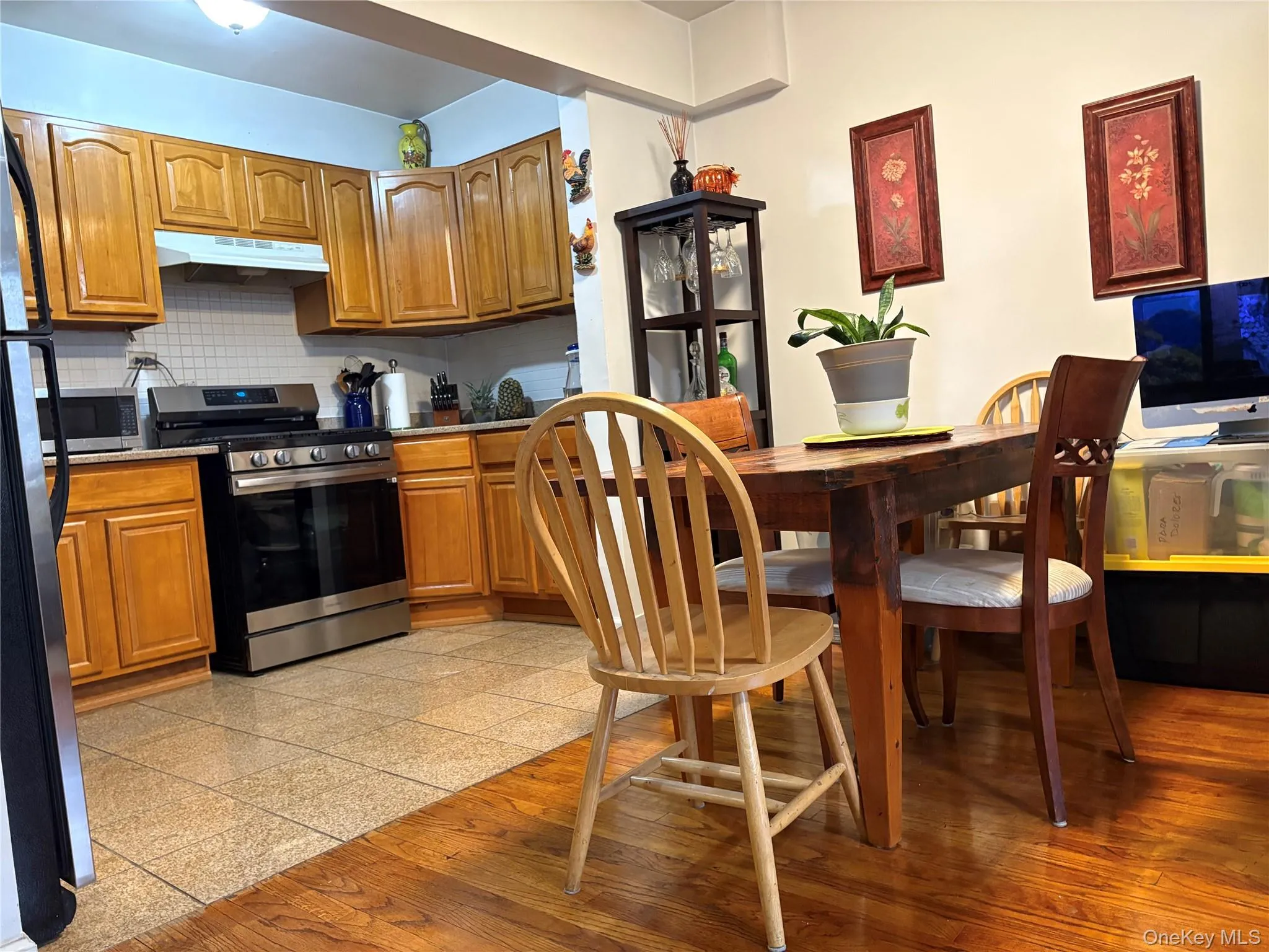 Kitchen with brown cabinetry, appliances with stainless steel finishes, under cabinet range hood, and granite tiled floors Kitchen with brown cabinetry, appliances with stainless steel finishes, under cabinet range hood, and granite tiled floors