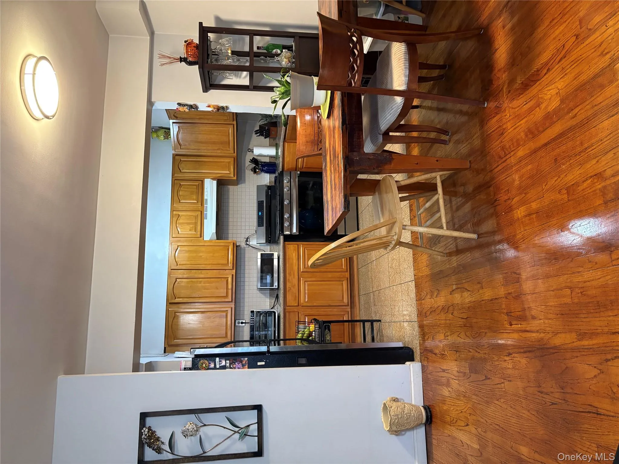 Kitchen featuring brown cabinetry, appliances with stainless steel finishes, decorative backsplash, light wood-style floors, and exhaust hood Kitchen featuring brown cabinetry, appliances with stainless steel finishes, decorative backsplash, light wood-style floors, and exhaust hood