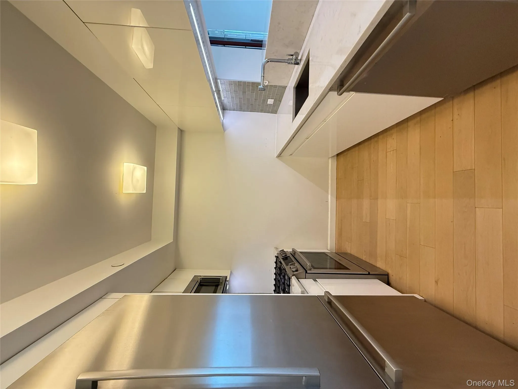 Kitchen featuring white cabinets, appliances with stainless steel finishes, light stone counters, light wood-style flooring, and backsplash Kitchen featuring white cabinets, appliances with stainless steel finishes, light stone counters, light wood-style flooring, and backsplash