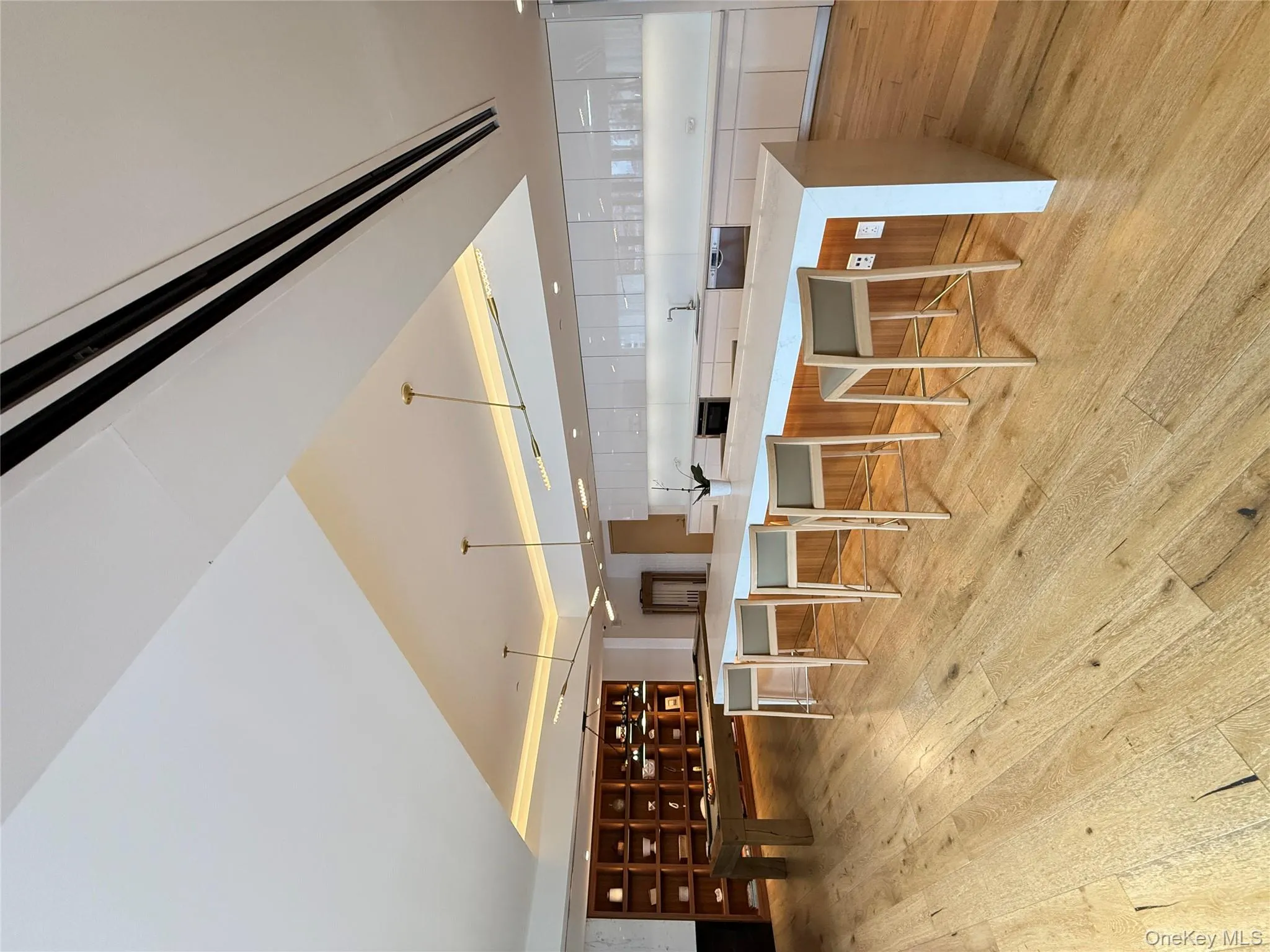 Kitchen with white cabinetry, hanging light fixtures, light stone counters, a breakfast bar, and modern cabinets Kitchen with white cabinetry, hanging light fixtures, light stone counters, a breakfast bar, and modern cabinets