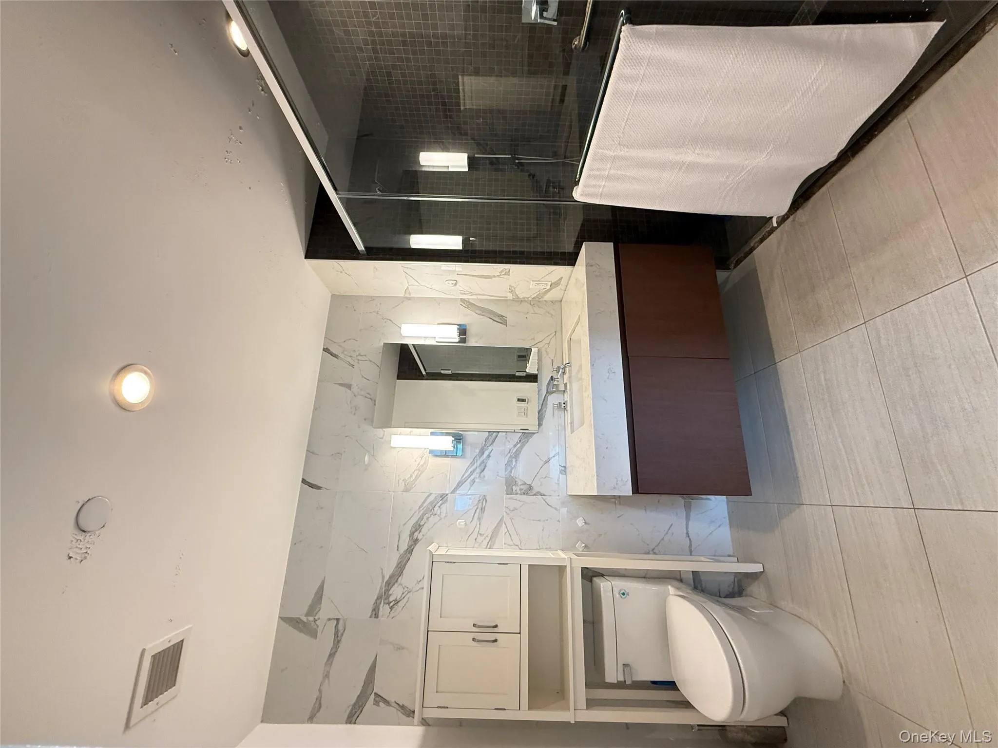 Full bathroom featuring tile walls, a shower stall, vanity, stone wall, and light tile patterned floors Full bathroom featuring tile walls, a shower stall, vanity, stone wall, and light tile patterned floors