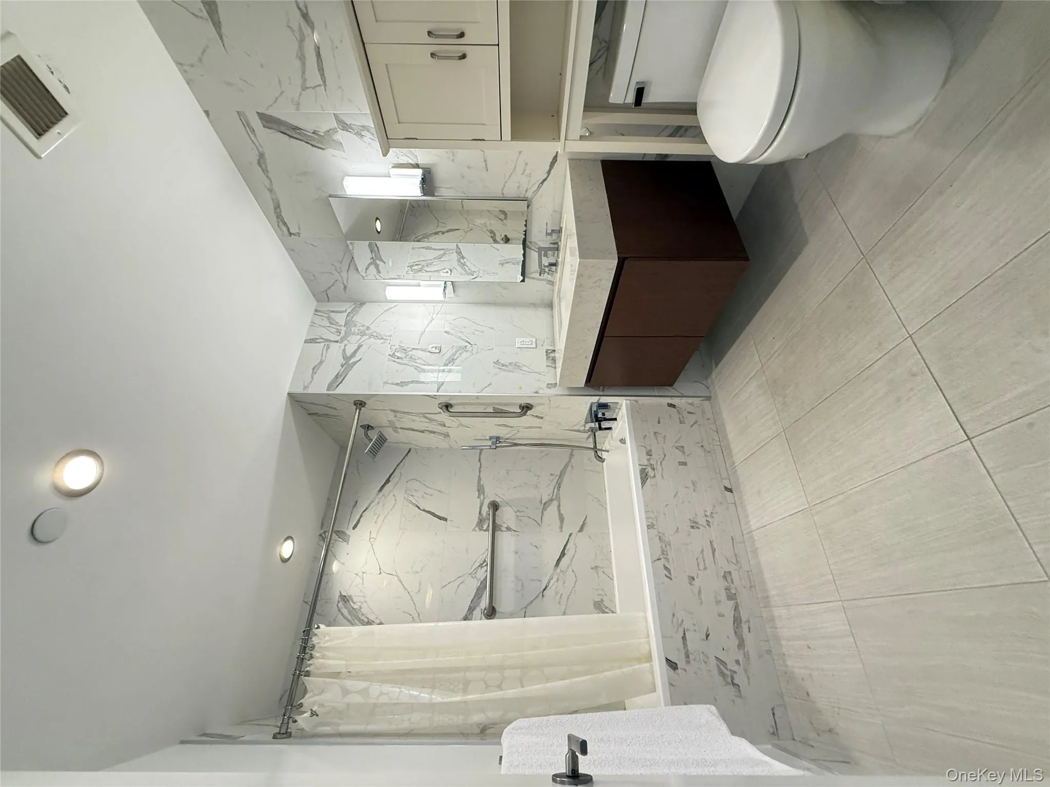 Full bath with vanity, a combined bath / shower with marble appearance, tile walls, and recessed lighting Full bath with vanity, a combined bath / shower with marble appearance, tile walls, and recessed lighting