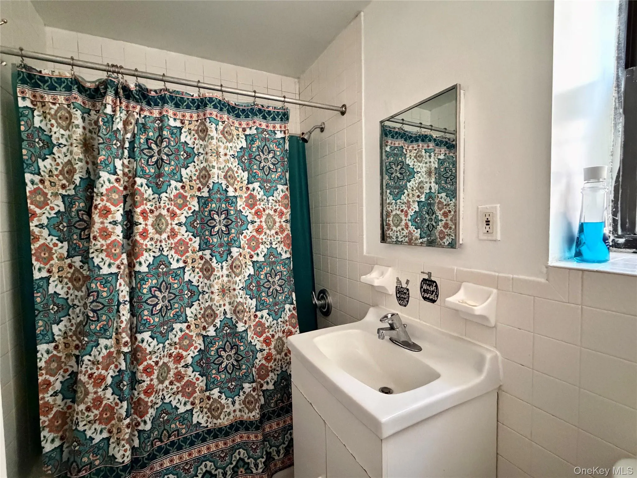Full bath with tile walls, vanity, and a shower with curtain Full bath with tile walls, vanity, and a shower with curtain