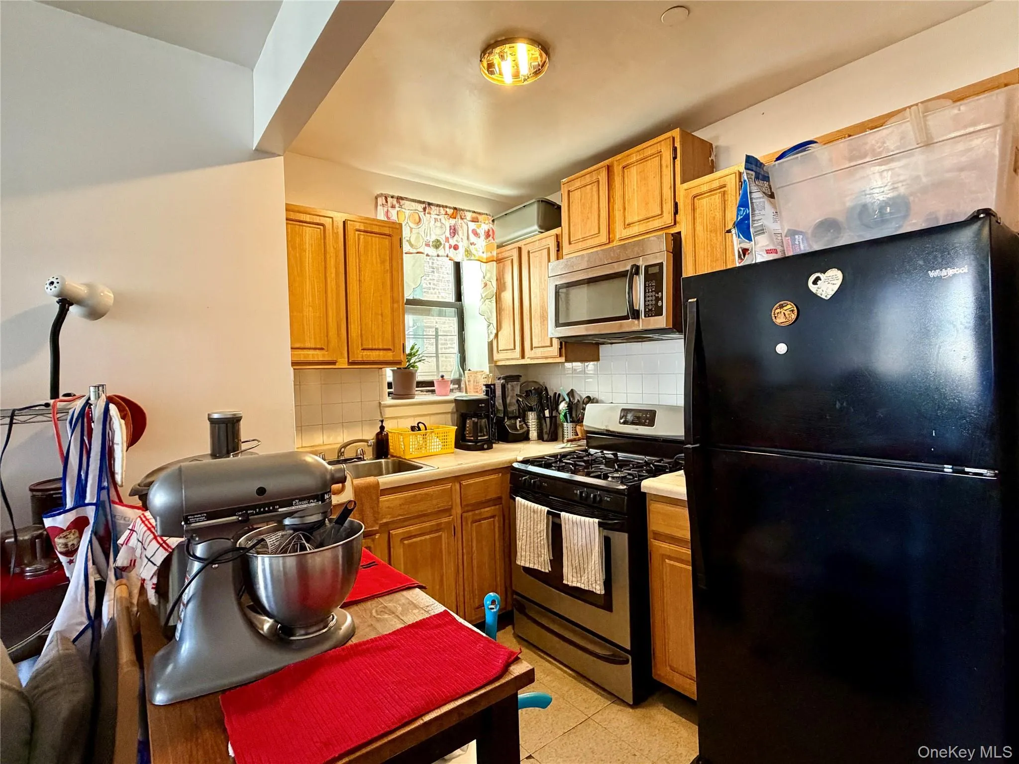 Kitchen featuring appliances with stainless steel finishes, light countertops, decorative backsplash, and light floors Kitchen featuring appliances with stainless steel finishes, light countertops, decorative backsplash, and light floors
