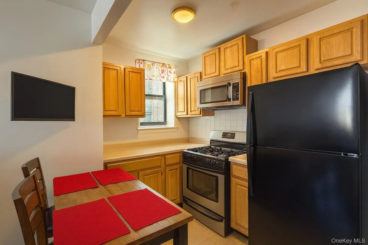 Kitchen with stainless steel appliances, light countertops, decorative backsplash, and light tile patterned flooring Kitchen with stainless steel appliances, light countertops, decorative backsplash, and light tile patterned flooring