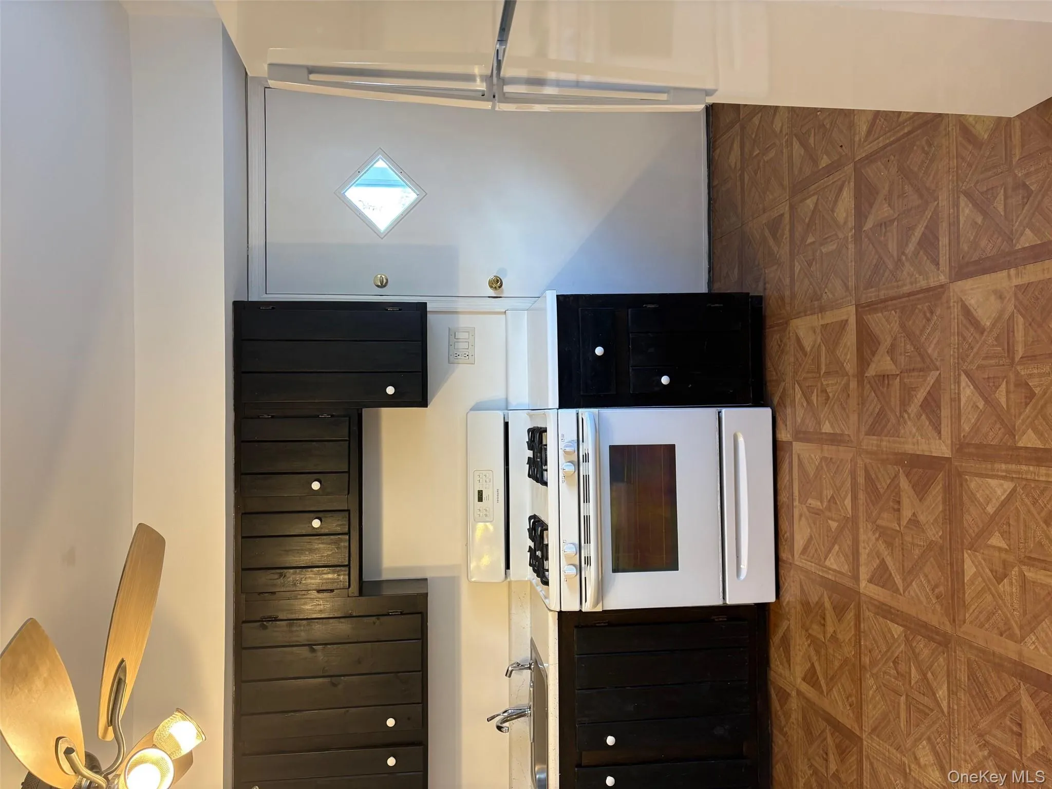 Kitchen with stove, refrigerator, light countertops, dark cabinets, and a ceiling fan Kitchen with stove, refrigerator, light countertops, dark cabinets, and a ceiling fan