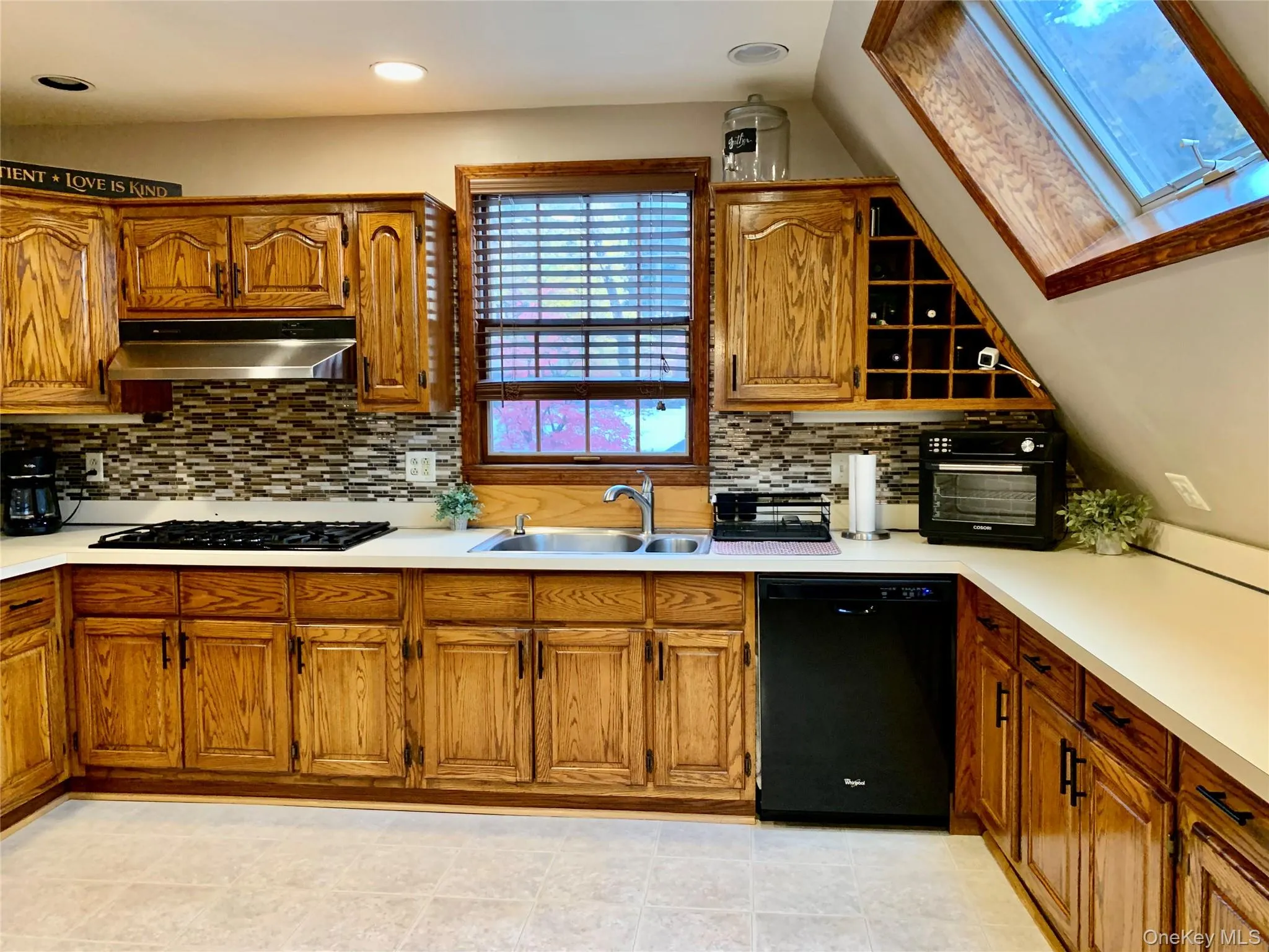 Kitchen with black appliances, light countertops, brown cabinetry, lofted ceiling, and recessed lighting Kitchen with black appliances, light countertops, brown cabinetry, lofted ceiling, and recessed lighting