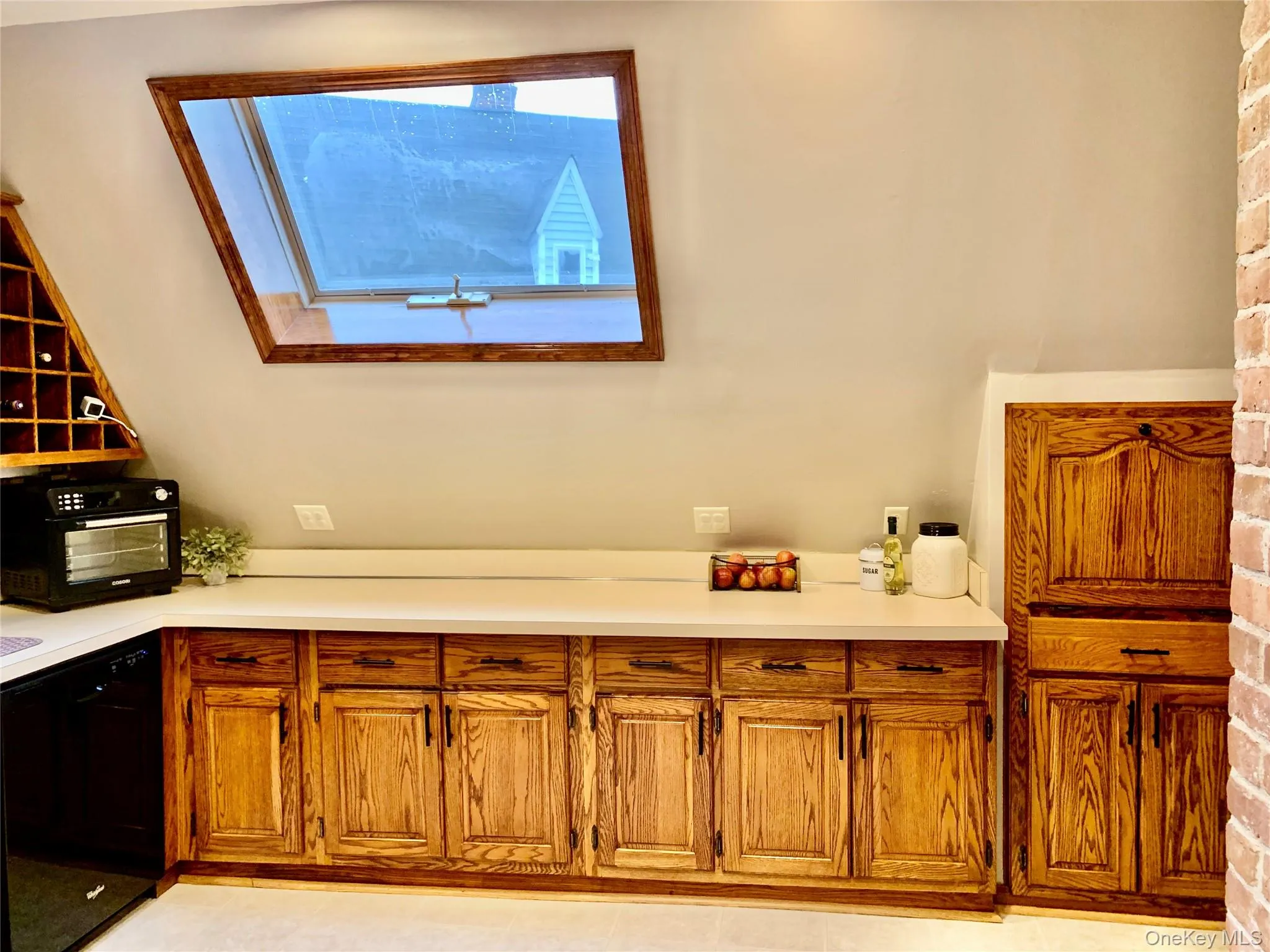 Bar area featuring dishwasher, brown cabinetry, and light countertops Bar area featuring dishwasher, brown cabinetry, and light countertops