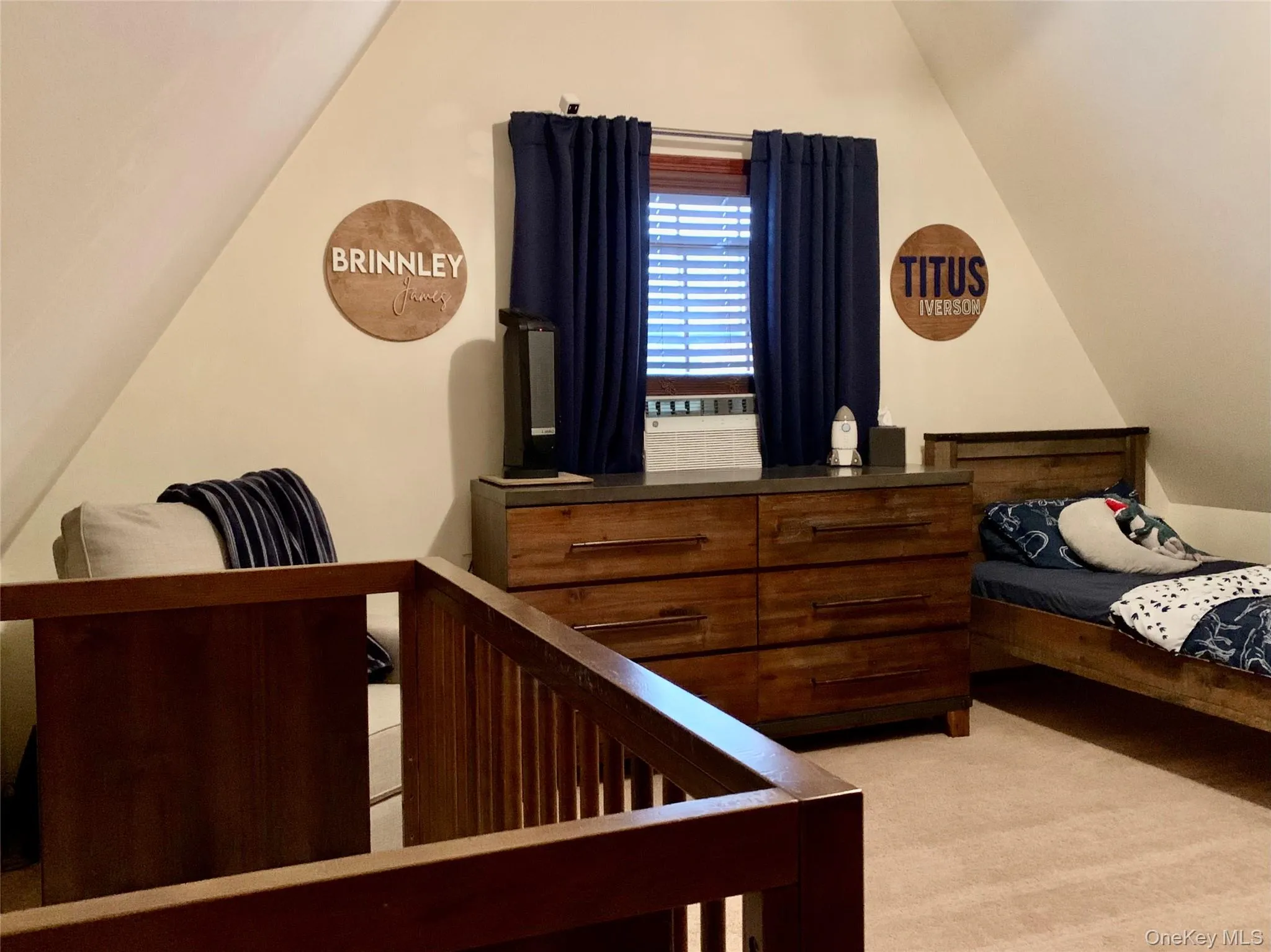Bedroom featuring lofted ceiling, light colored carpet, and a crib Bedroom featuring lofted ceiling, light colored carpet, and a crib