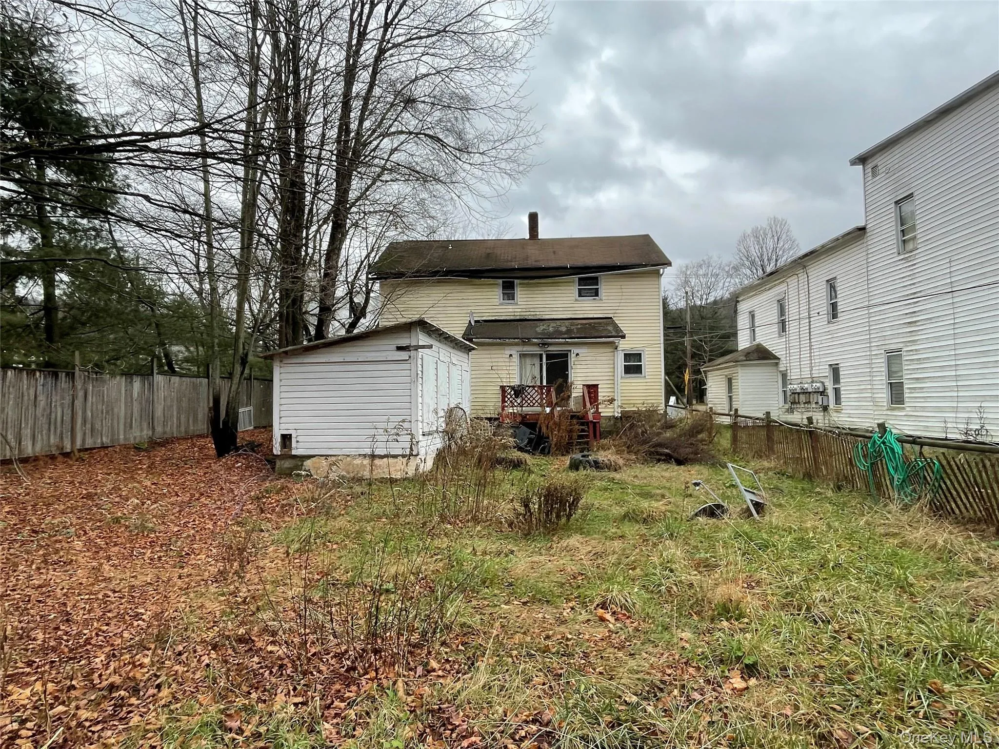 Back of house with a fenced backyard, a deck, and an outbuilding Back of house with a fenced backyard, a deck, and an outbuilding