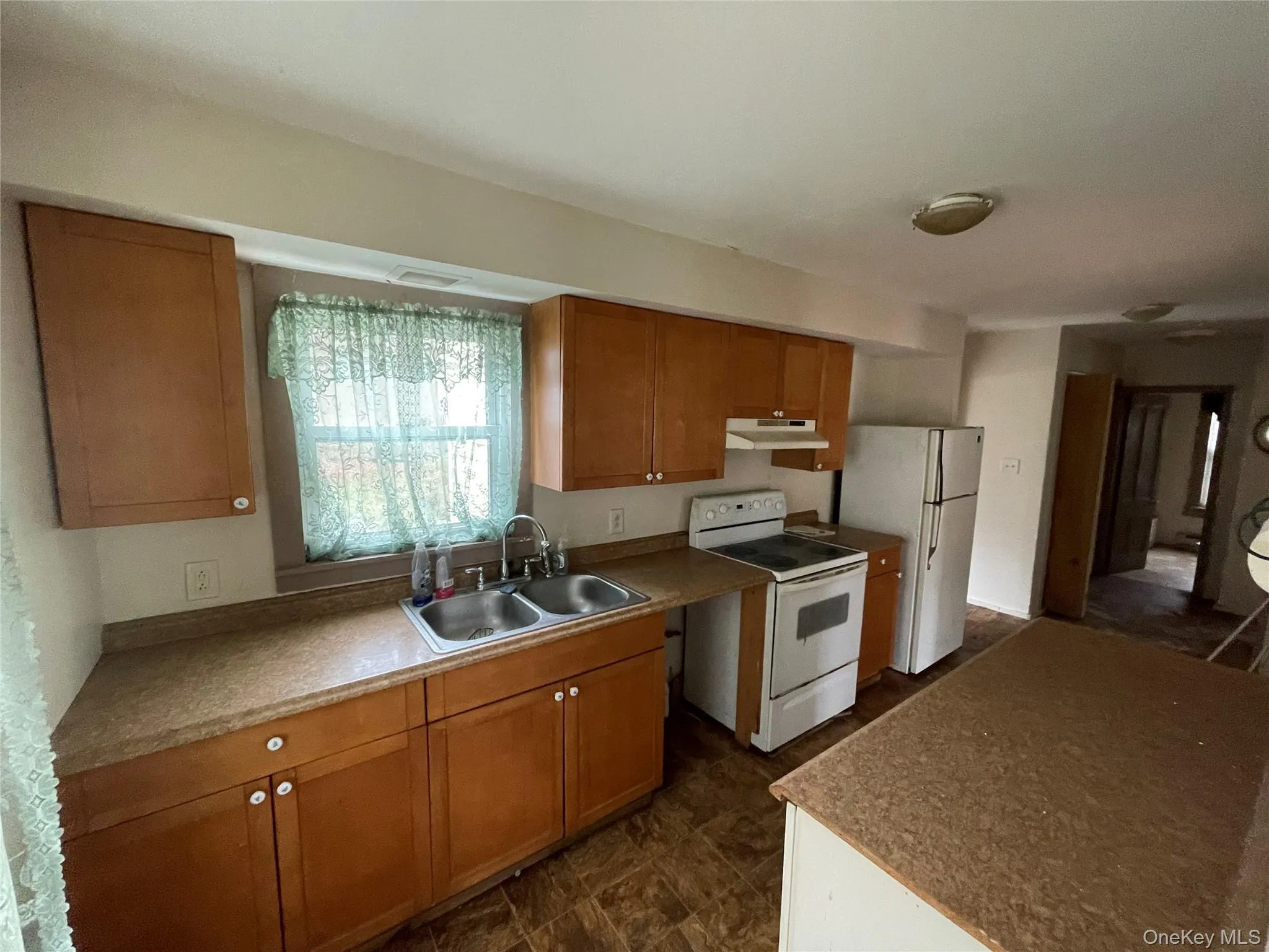 Kitchen featuring white appliances, brown cabinets, and under cabinet range hood Kitchen featuring white appliances, brown cabinets, and under cabinet range hood