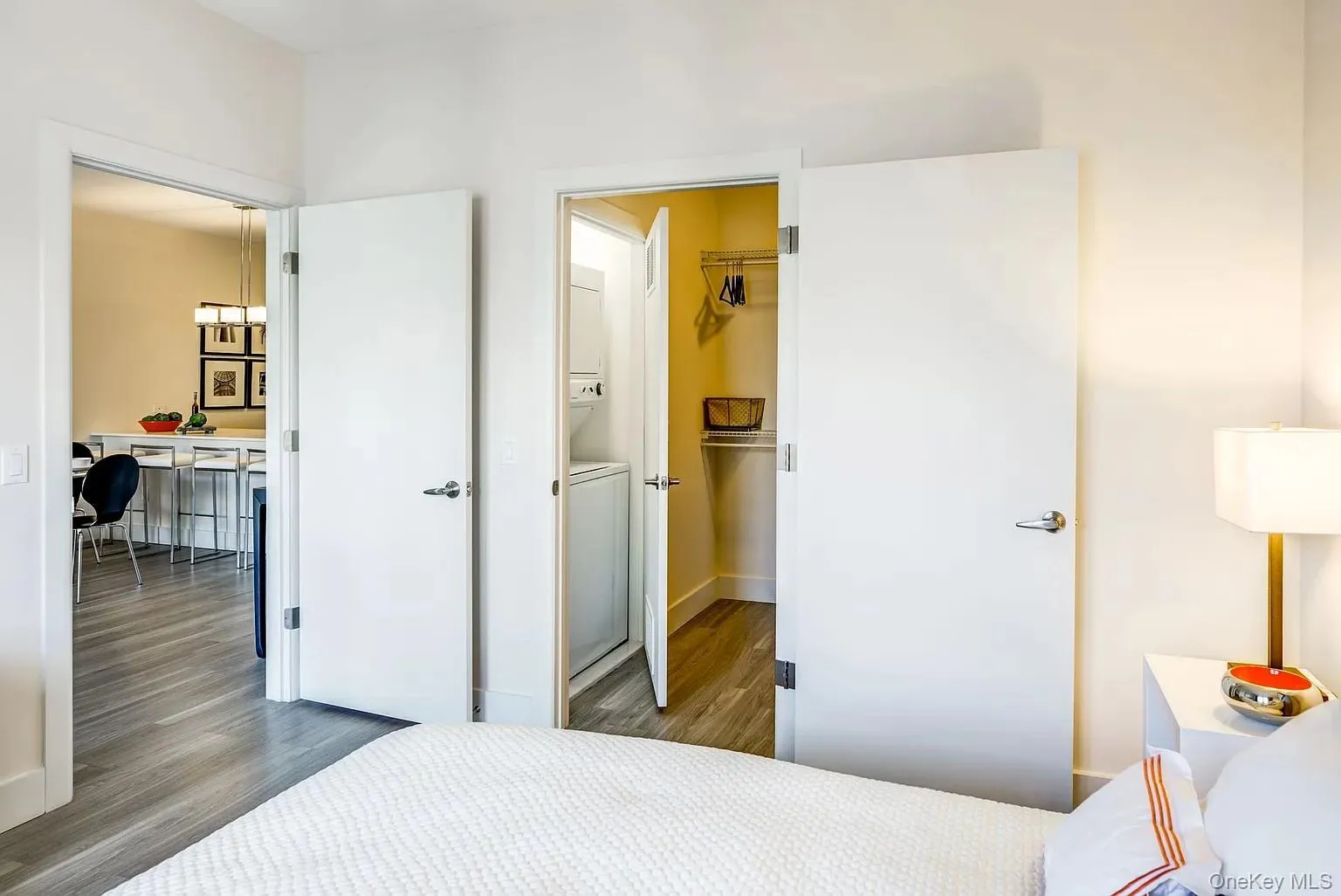 Bedroom featuring a spacious closet, wood finished floors, a chandelier, and stacked washer / dryer Bedroom featuring a spacious closet, wood finished floors, a chandelier, and stacked washer / dryer