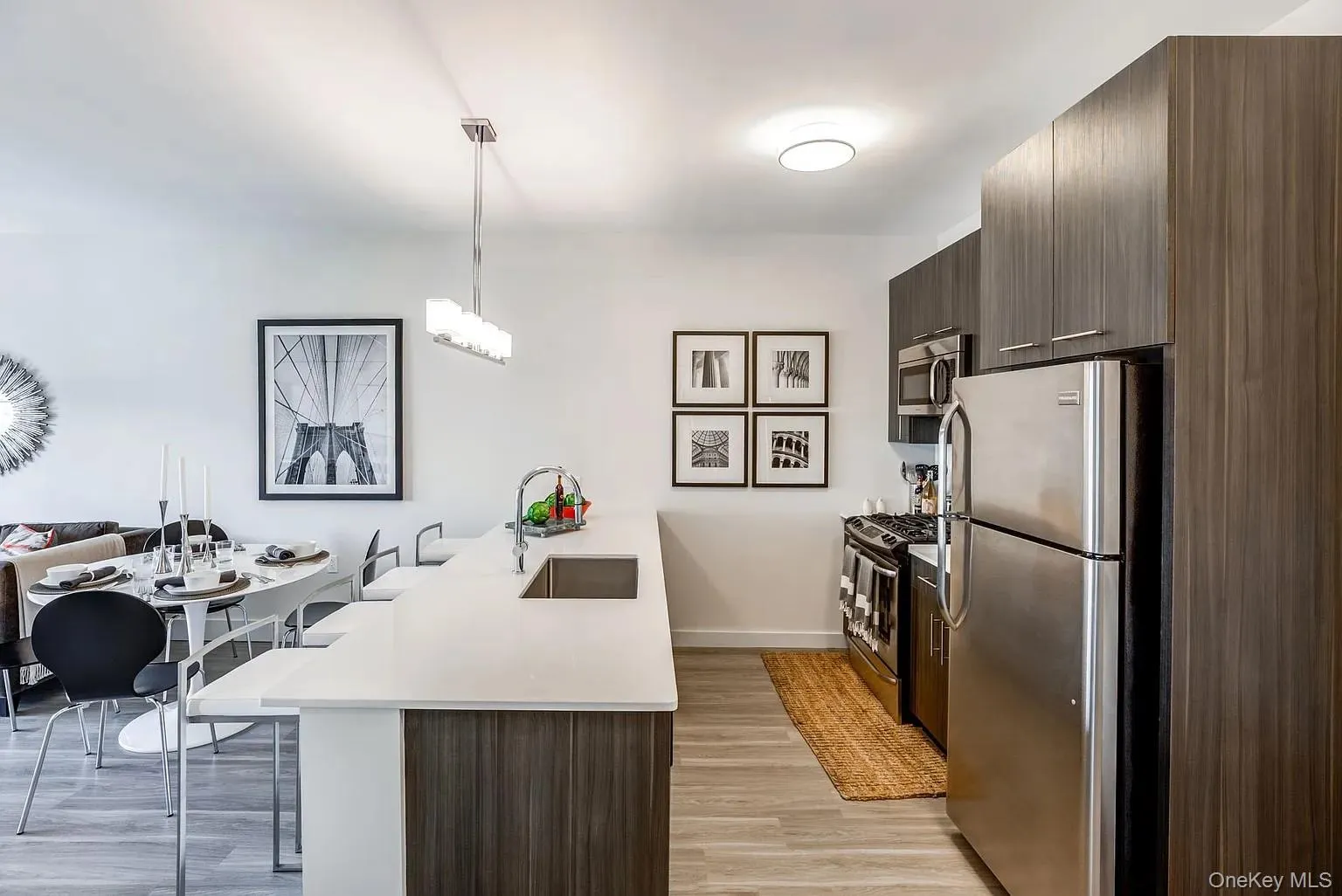 Kitchen with dark brown cabinetry, a breakfast bar area, modern cabinets, stainless steel appliances, and a peninsula Kitchen with dark brown cabinetry, a breakfast bar area, modern cabinets, stainless steel appliances, and a peninsula