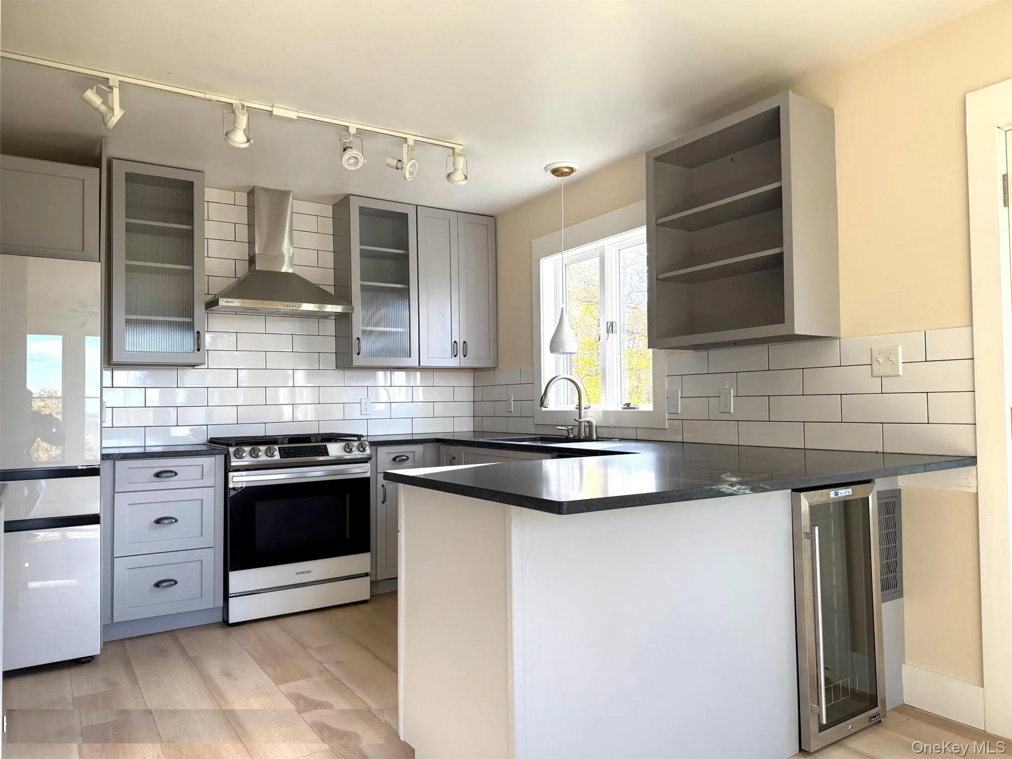 Kitchen featuring a peninsula, gray cabinetry, wall exhaust hood, and stainless steel range Kitchen featuring a peninsula, gray cabinetry, wall exhaust hood, and stainless steel range
