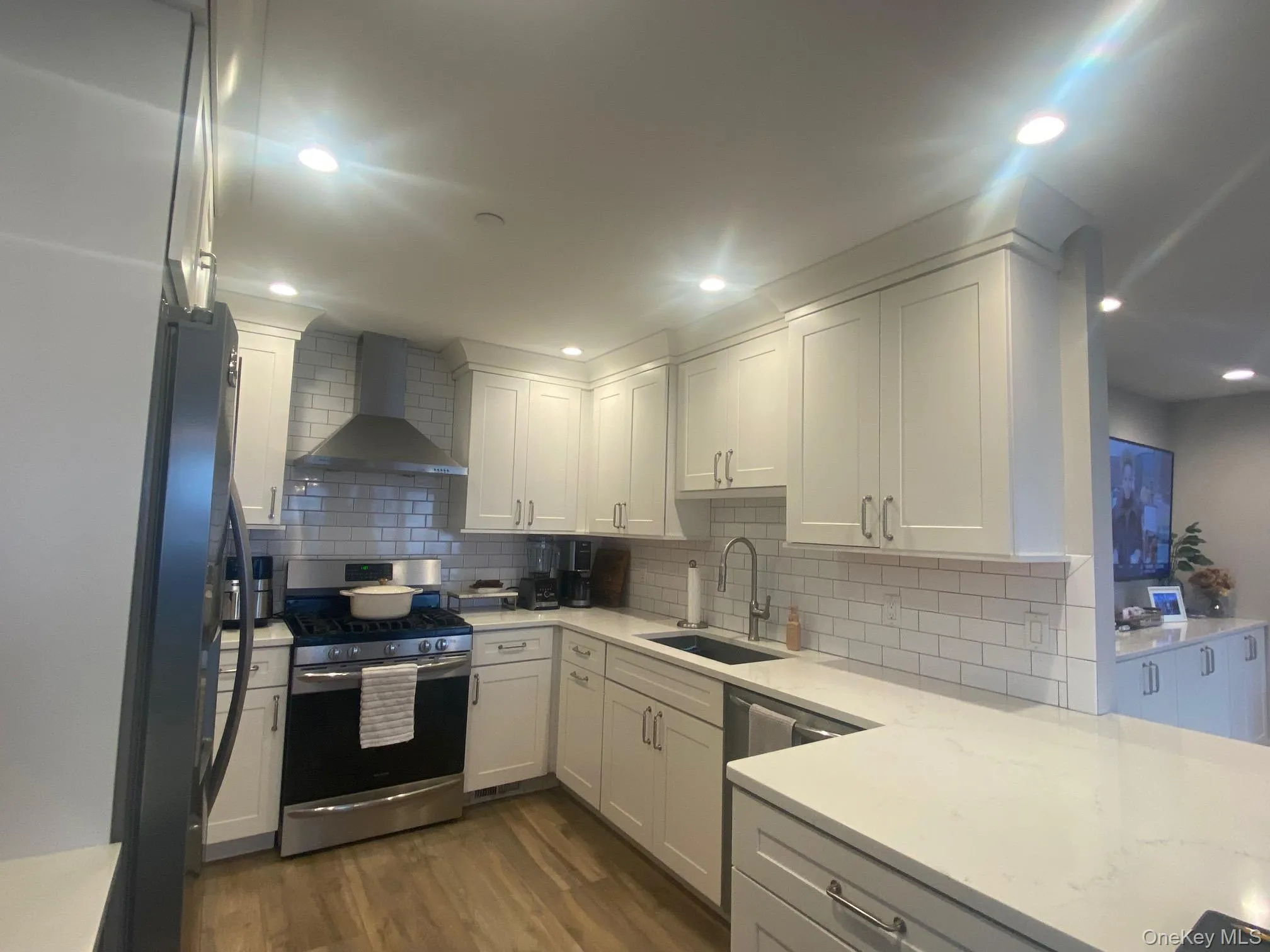 Kitchen featuring gas range, exhaust hood, white cabinets, and freestanding refrigerator Kitchen featuring gas range, exhaust hood, white cabinets, and freestanding refrigerator