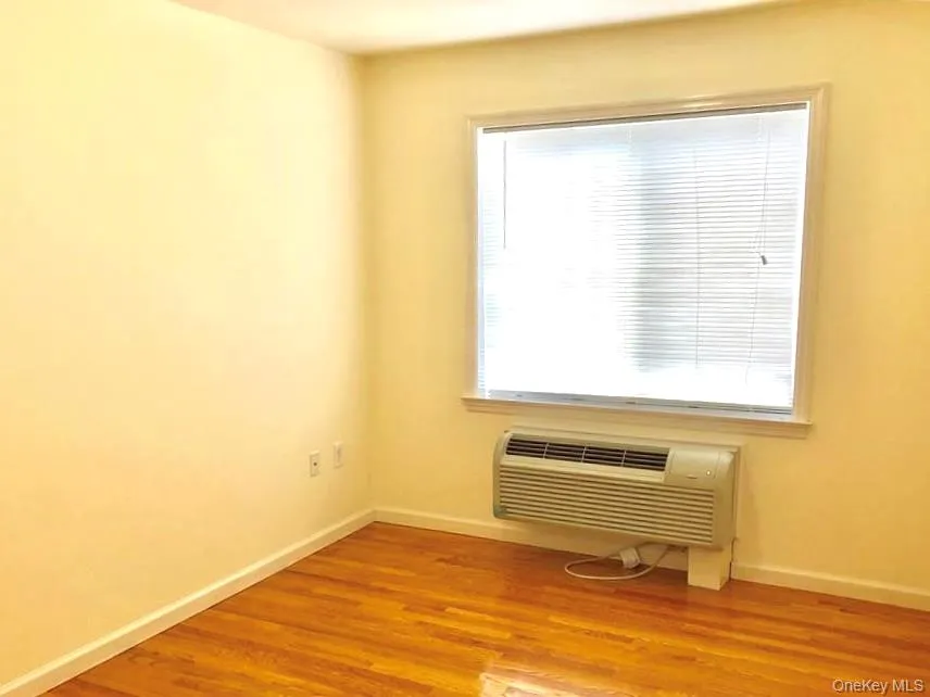 Unfurnished room featuring light wood-style flooring and a wall mounted air conditioner Unfurnished room featuring light wood-style flooring and a wall mounted air conditioner