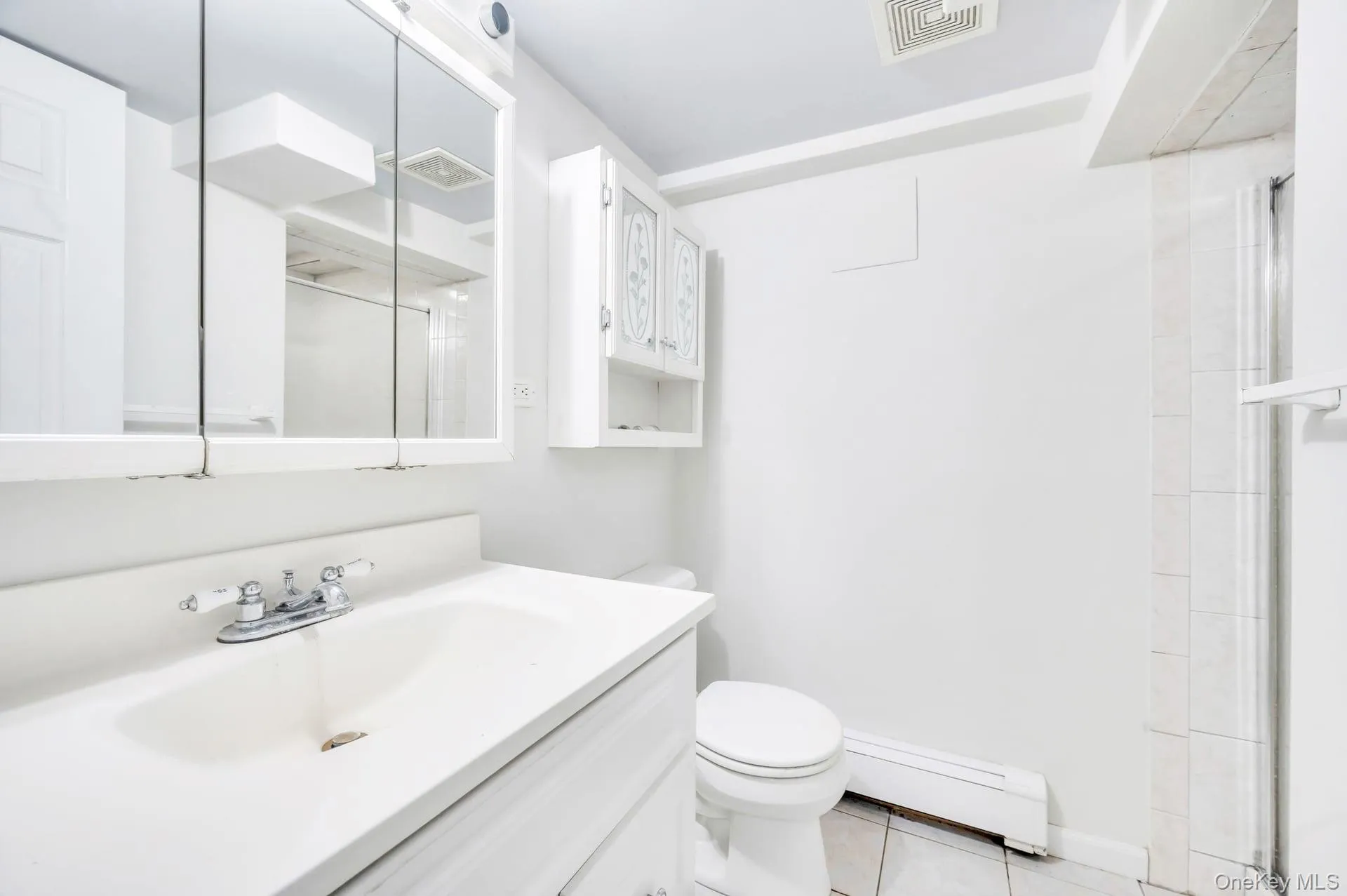 Full bath featuring baseboard heating, vanity, an enclosed shower, and tile patterned floors Full bath featuring baseboard heating, vanity, an enclosed shower, and tile patterned floors