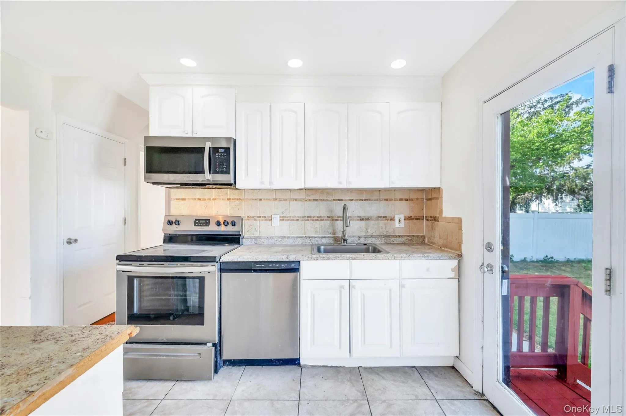 Kitchen featuring appliances with stainless steel finishes, tasteful backsplash, white cabinets, light tile patterned floors, and recessed lighting Kitchen featuring appliances with stainless steel finishes, tasteful backsplash, white cabinets, light tile patterned floors, and recessed lighting