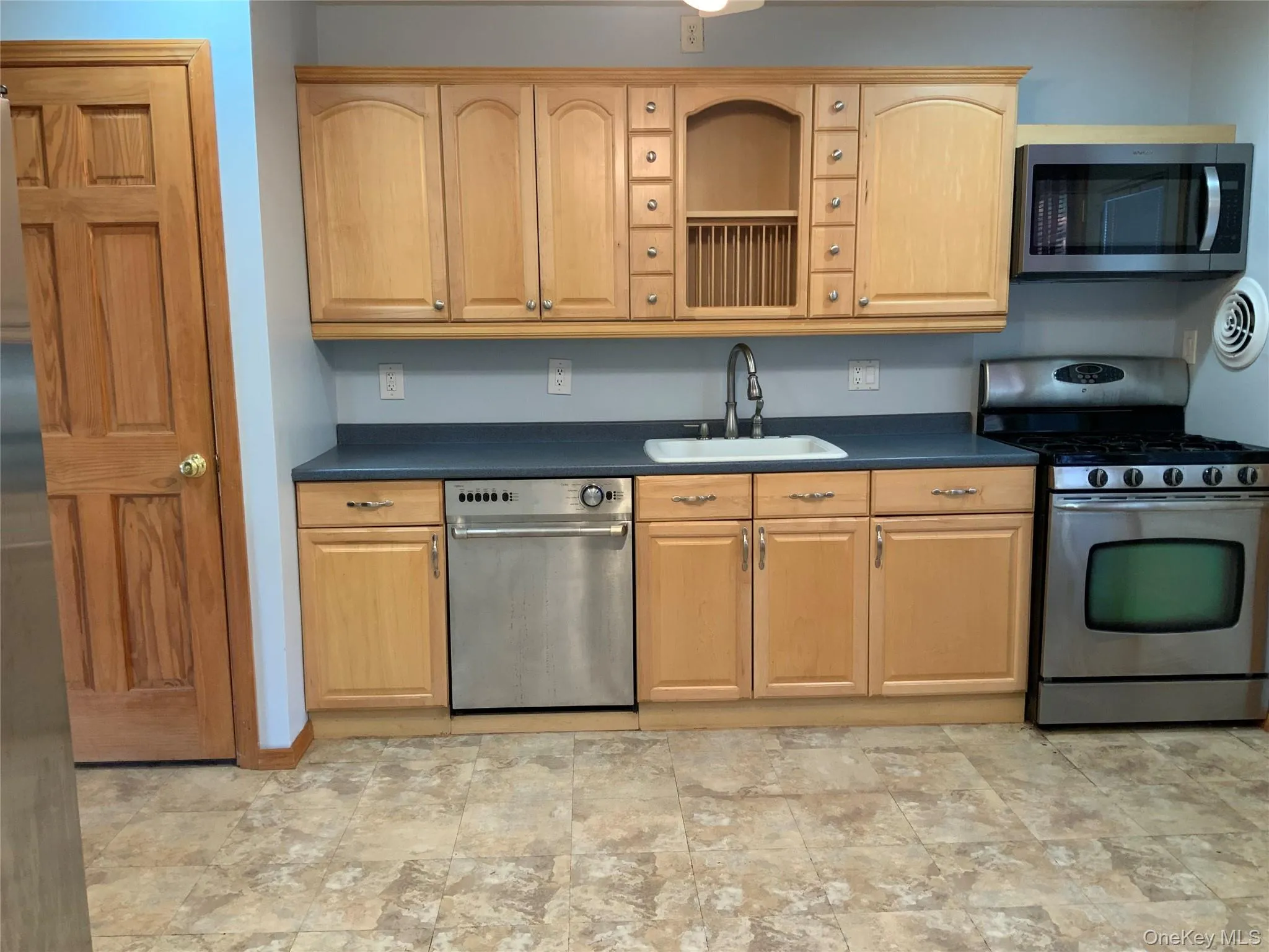 Kitchen with dark countertops, stainless steel appliances, light brown cabinetry Kitchen with dark countertops, stainless steel appliances, light brown cabinetry