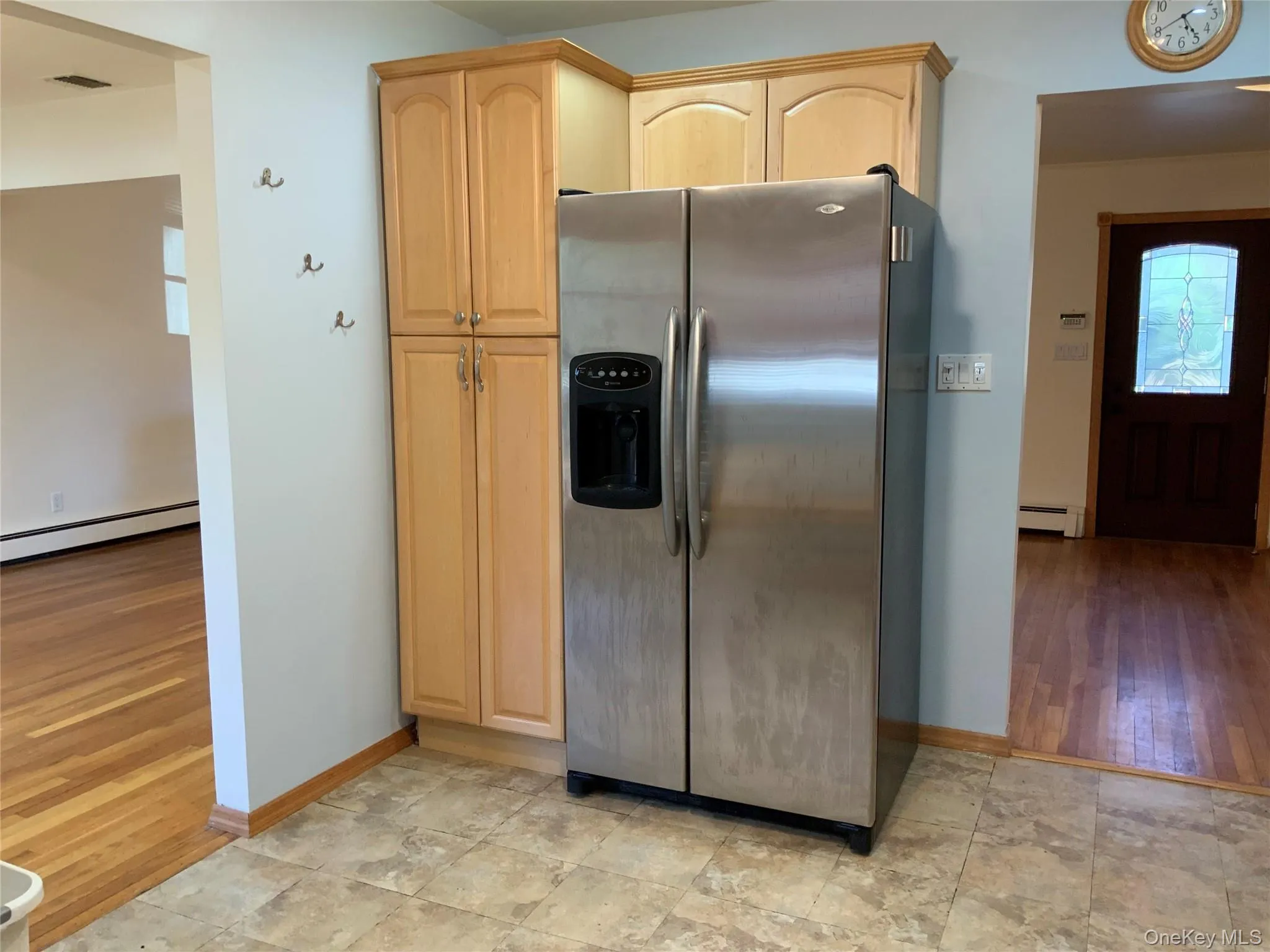 Kitchen with stainless steel refrigerator with ice dispenser, light brown cabinetry, baseboard heating Kitchen with stainless steel refrigerator with ice dispenser, light brown cabinetry, baseboard heating
