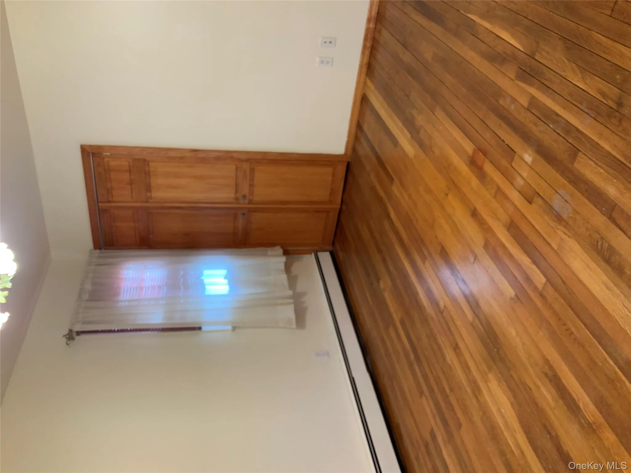 Unfurnished bedroom featuring a baseboard radiator, a closet, and hardwood / wood-style flooring Unfurnished bedroom featuring a baseboard radiator, a closet, and hardwood / wood-style flooring