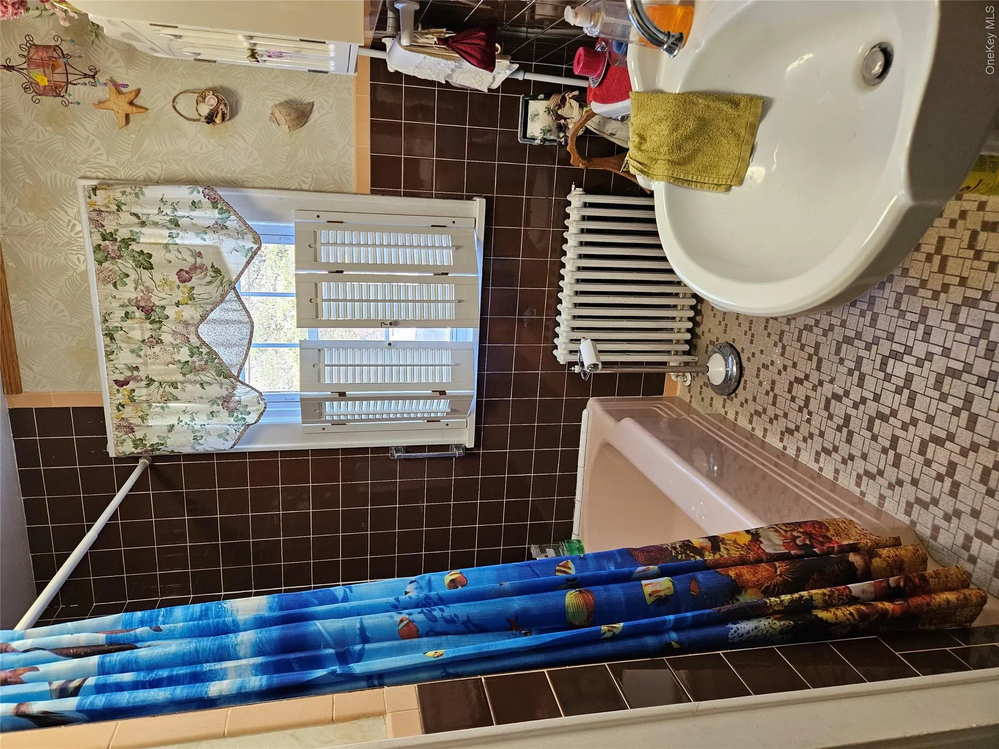 Full bath with radiator heating unit, shower / bath combo, tile walls, wallpapered walls, and tile patterned floors Full bath with radiator heating unit, shower / bath combo, tile walls, wallpapered walls, and tile patterned floors