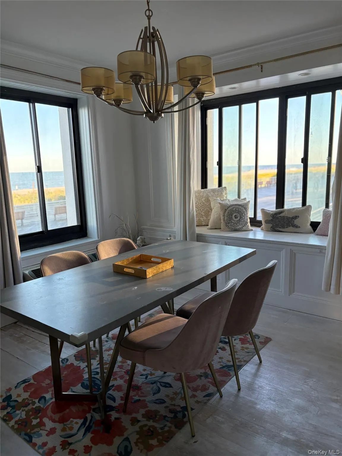 Dining area with a chandelier, crown molding, light wood-style flooring, and a water view Dining area with a chandelier, crown molding, light wood-style flooring, and a water view