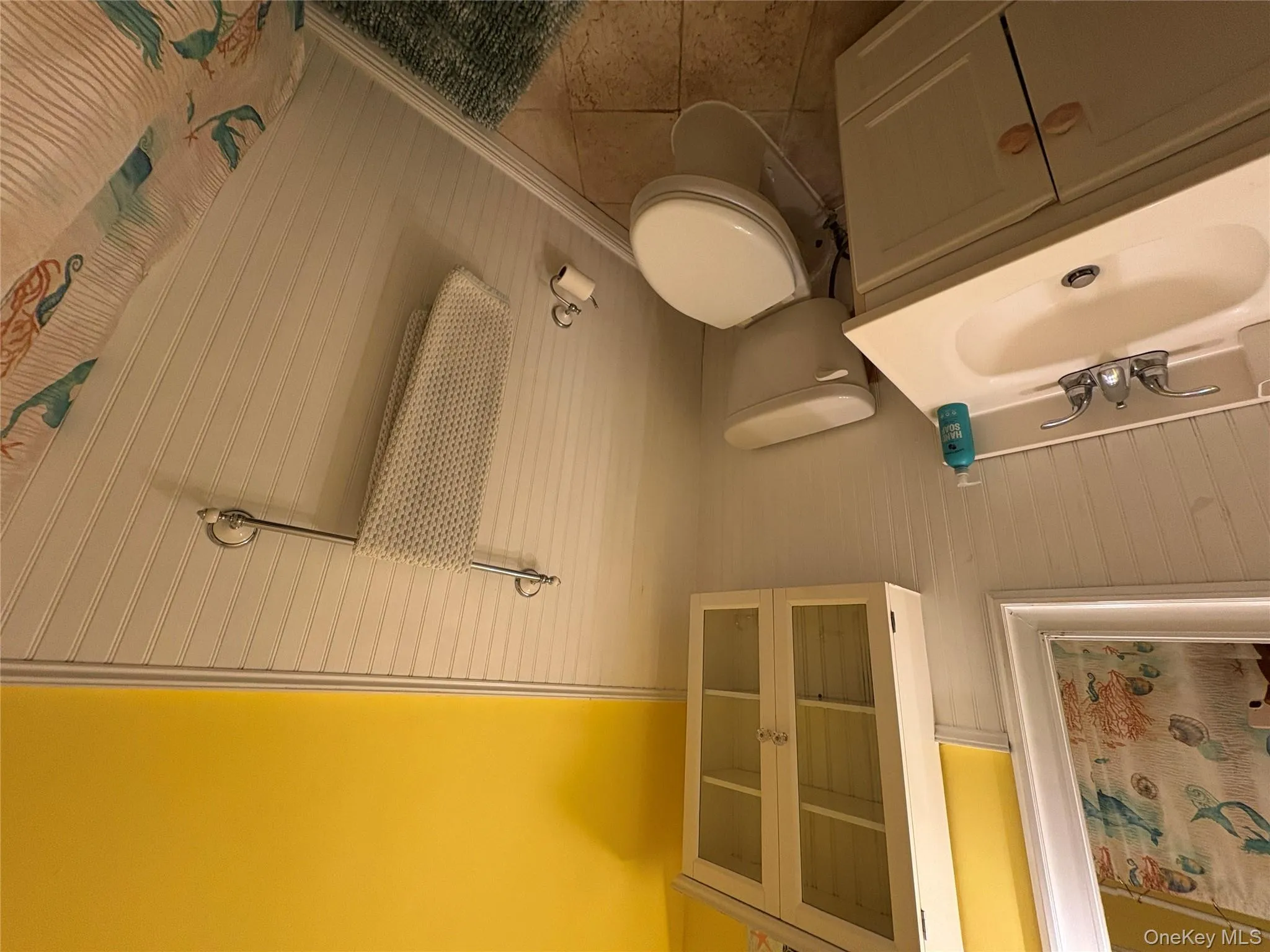 Bathroom with wainscoting, a shower with shower curtain, vanity, light tile patterned floors, and wood walls Bathroom with wainscoting, a shower with shower curtain, vanity, light tile patterned floors, and wood walls