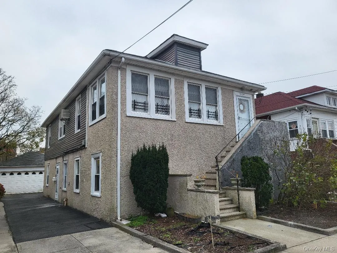 View of front of property with stucco siding, stairway, a garage, and a wall unit AC View of front of property with stucco siding, stairway, a garage, and a wall unit AC