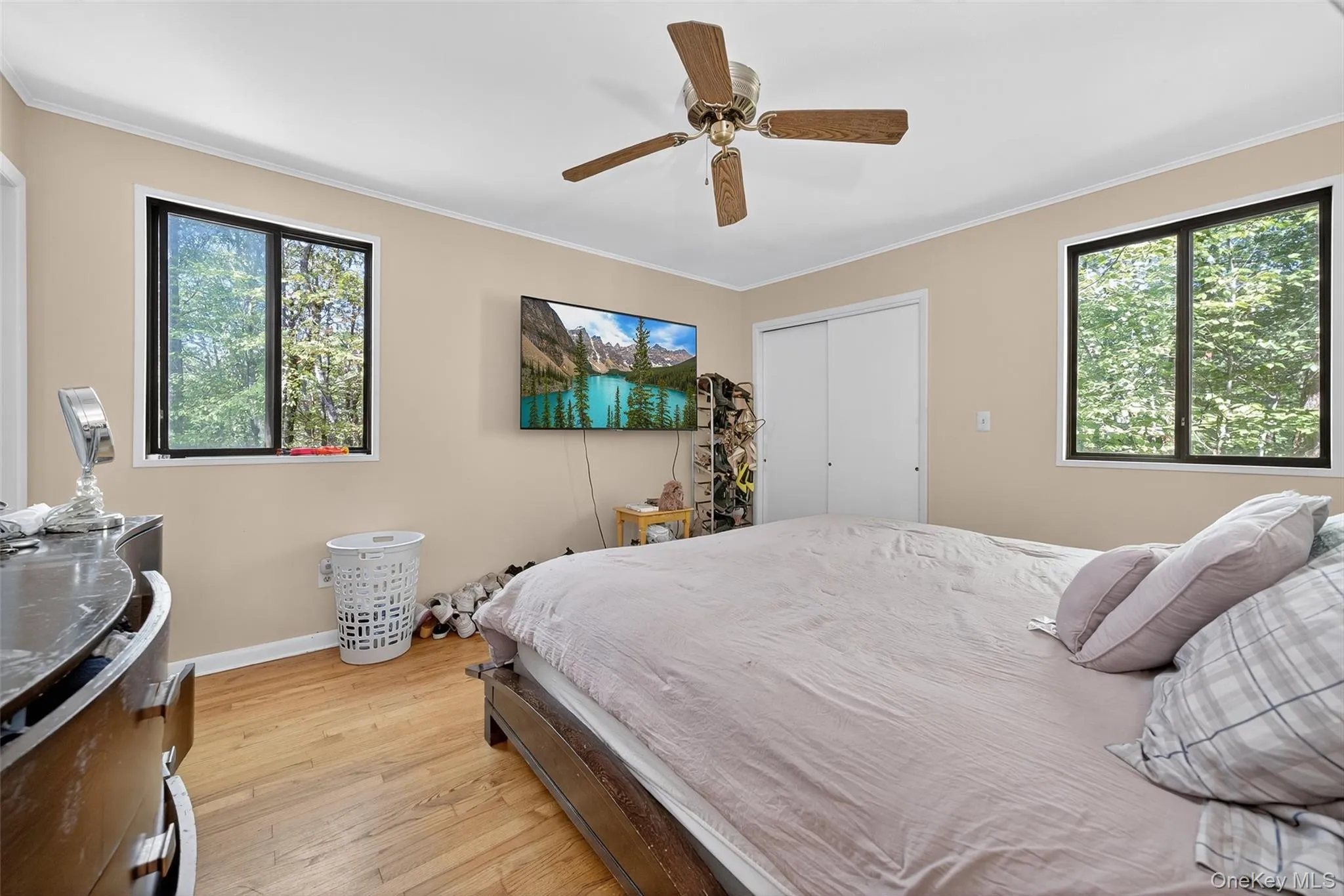Bedroom with ornamental molding, light wood finished floors, a ceiling fan, and a closet Bedroom with ornamental molding, light wood finished floors, a ceiling fan, and a closet
