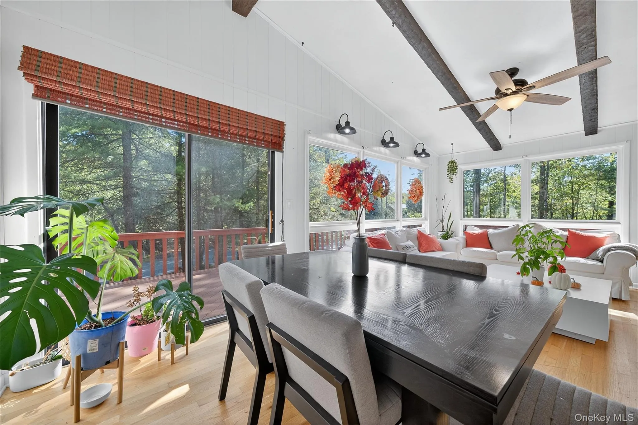 Sunroom / solarium featuring beam ceiling, wood finished floors, and high vaulted ceiling Sunroom / solarium featuring beam ceiling, wood finished floors, and high vaulted ceiling