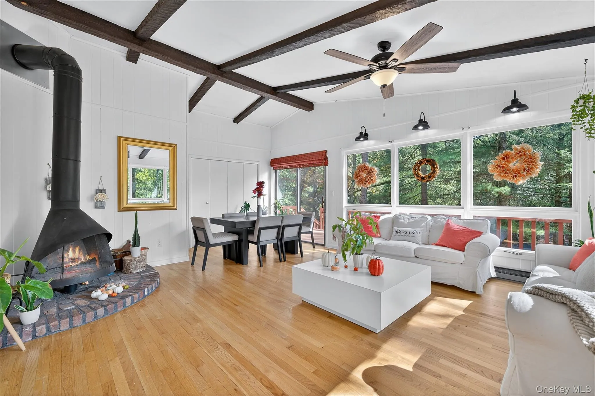 Living area featuring light wood-style flooring, a wood stove, and a ceiling fan Living area featuring light wood-style flooring, a wood stove, and a ceiling fan