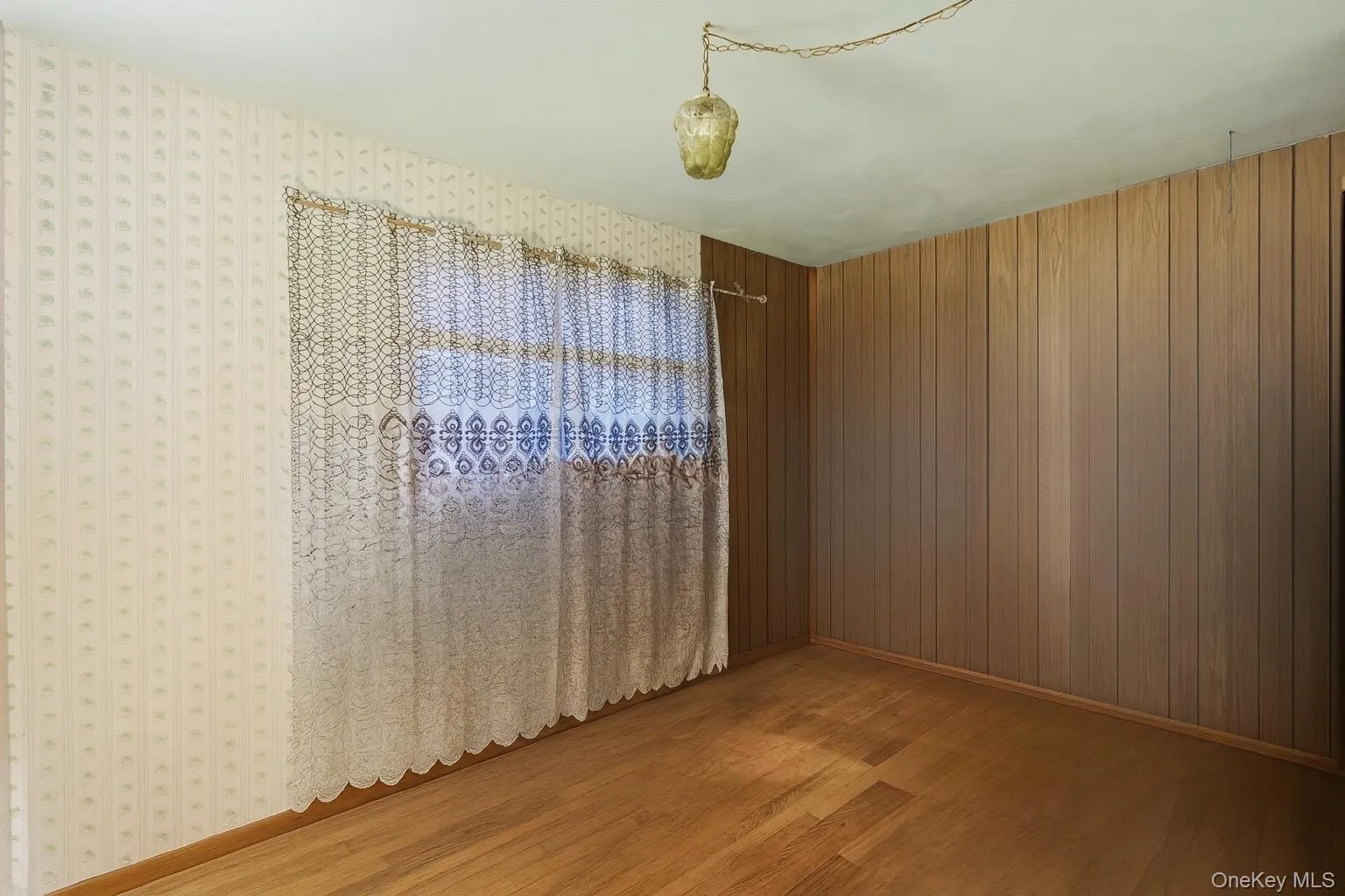 Unfurnished room with light wood-type flooring and wooden walls Unfurnished room with light wood-type flooring and wooden walls