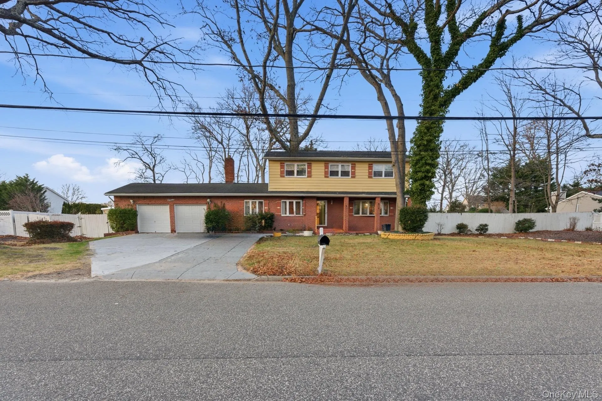 View of front facade featuring a chimney, concrete driveway, brick siding, and a garage View of front facade featuring a chimney, concrete driveway, brick siding, and a garage