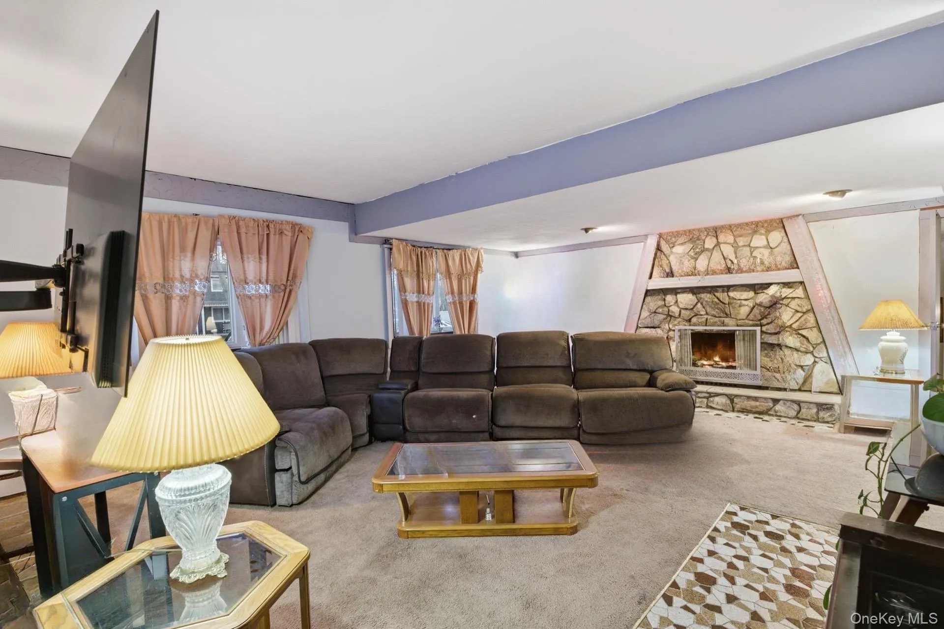 Carpeted living area featuring a stone fireplace Carpeted living area featuring a stone fireplace