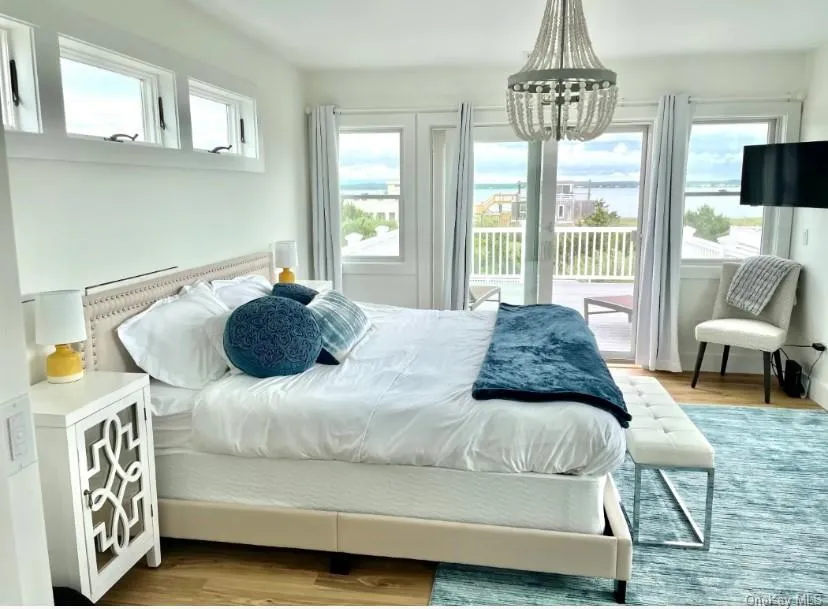 Bedroom with light wood-type flooring, multiple windows, access to outside, and a chandelier Bedroom with light wood-type flooring, multiple windows, access to outside, and a chandelier