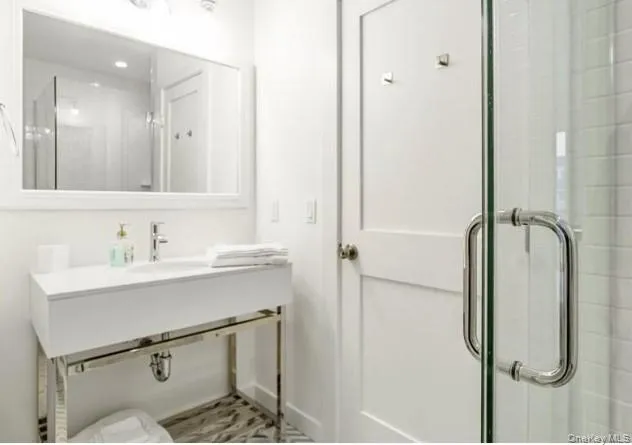 Full bath featuring a shower with door and a sink Full bath featuring a shower with door and a sink