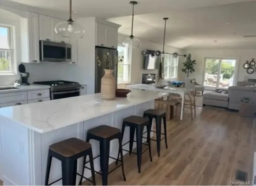 Kitchen featuring white cabinets, stainless steel appliances, open floor plan, and pendant lighting Kitchen featuring white cabinets, stainless steel appliances, open floor plan, and pendant lighting