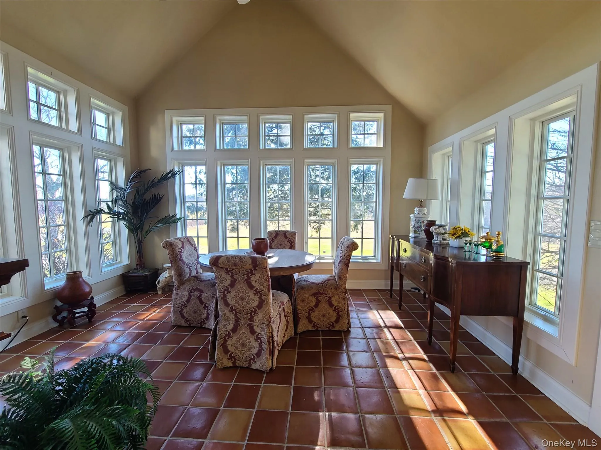Dining space featuring dark tile patterned flooring and high vaulted ceiling Dining space featuring dark tile patterned flooring and high vaulted ceiling