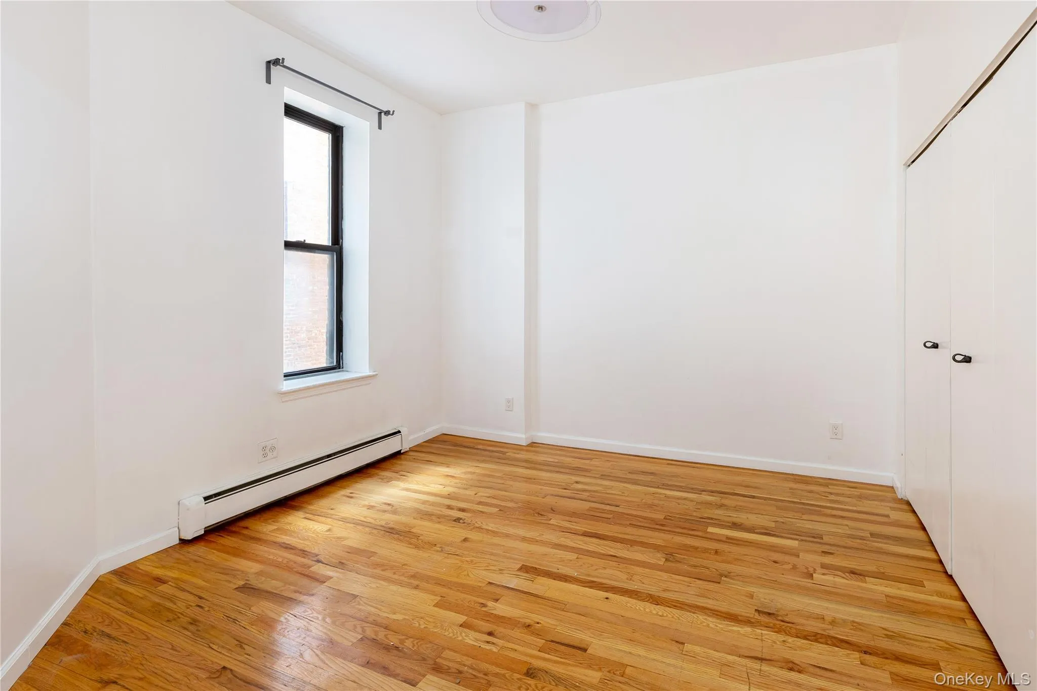 Spare room with baseboard heating and light wood-style floors Spare room with baseboard heating and light wood-style floors